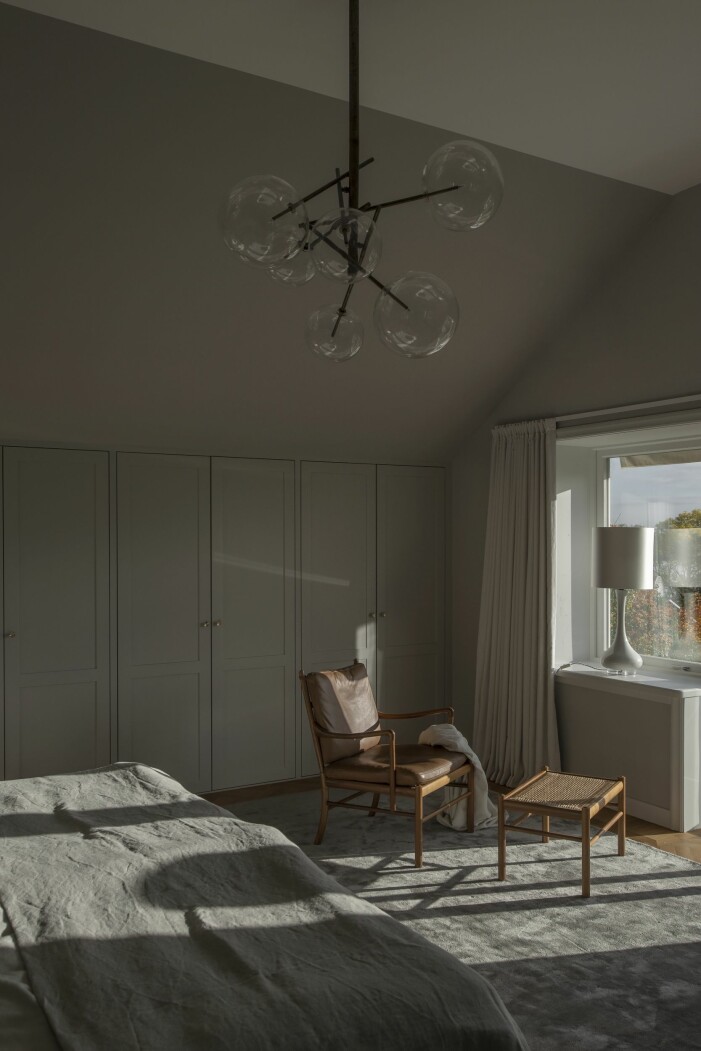 Kattvindarna i sovrummet har fått platsbyggda garderober. Taklampa i handblåst glas, Gallotti & Radice/Garbo interiors, lampa i fönstret, Porta romana, fåtölj Colonial chair, Länna möbler, matta, Layered. garderober i kattvindar