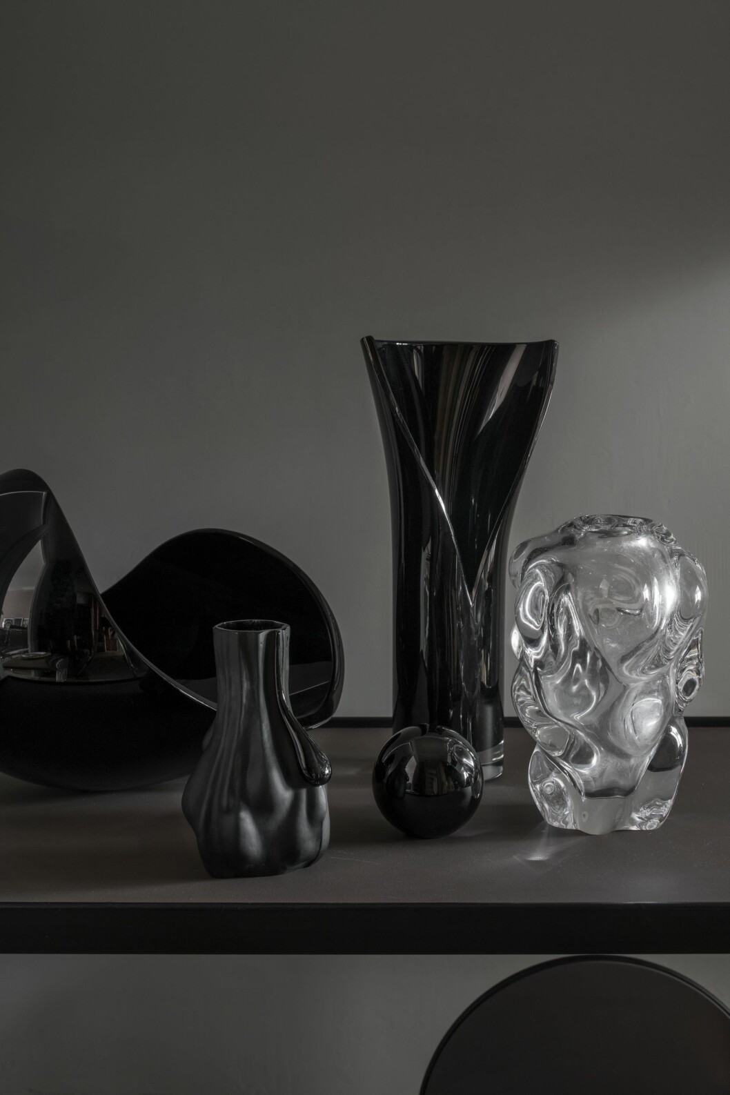 Karin samlar på svart glas. Objekt av Lena Bergström, Orrefors, och Per B Sundbergs Move i klarglas för Orrefors. Liten blästrad vas av Markus Emilsson för Målerås glasbruk. Glasobjekt av Lena Bergström, Orrefors, och Per B Sundbergs Move i klarglas för Orrefors. Liten blästrad vas av Markus Emilsson för Målerås glasbruk.