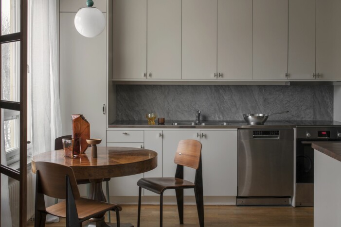 Köket var befintligt, men Karin har lackat om luckorna i Kvänums kulör Ax och byggt in skåpen. Handtag Vide från Kvänum. Stänkskydd Quartzit grey från Bricmate. På diskbänken i rostfritt stål står en Fiskars wokpanna. Stolar av Jean Prouvé, Standard chair. Kök med lackade köksluckor i Kvänums kulör Ax och ett matbord med stolar av Jean Prouvé.