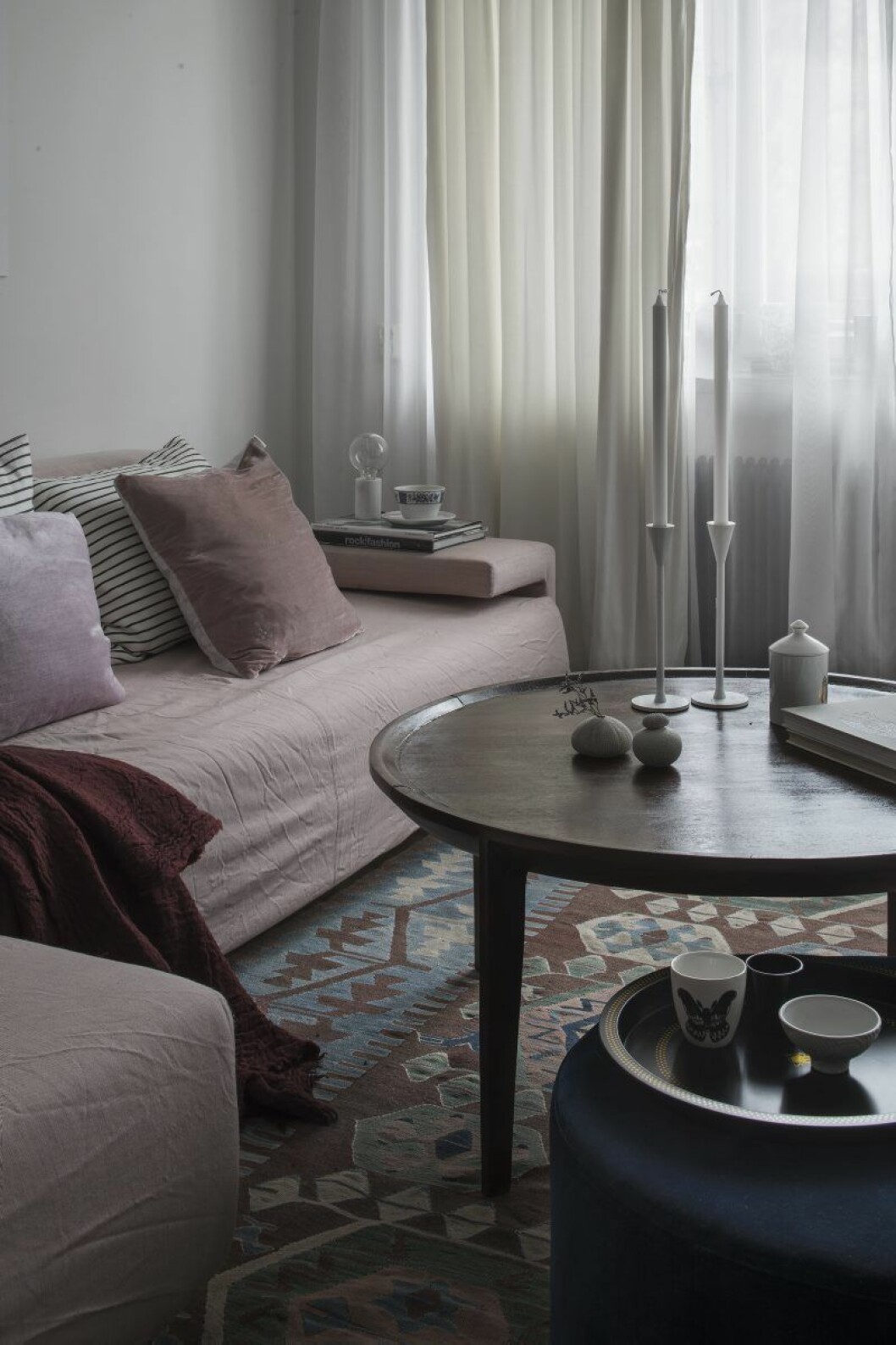 Ena delen av vardagsrummet fungerar som ett ljust sällskapsrum. Soffa NK inredning, bord Jotex, lampa med marmorfot Lamp-Niklas, kuddar Habitat. Sittpuff Melimeli. På denna står Anithas nya bricka och kopp. På bordet ljusstakar från Asplund, sjöborre från Kenya och ett doftljus från Candelize. Soffa NK hemma hos Anitha Clemence