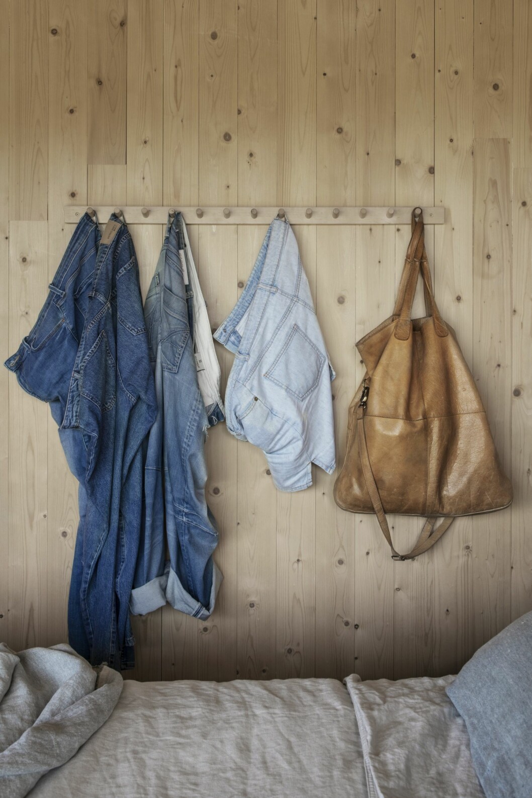 Jeansstilleben i sovrummet. Plagg i denim på knopphängare i sovrummet.