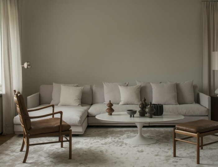 Ljuset ändrar väggfärgen, från ljusgrått till milt grön, färgen heter Strongwhite, Farrow & Ball. Soffa, Eilersen, fåtölj med fotpall Colonial chair, Länna möbler, soffbord Tulip av Eero Saarinen, lampa, Porta romana står på det lilla bordet Palais, Asplund, matta, Jacaranda, keramik, Dusty deco och kruka, Tufva design.