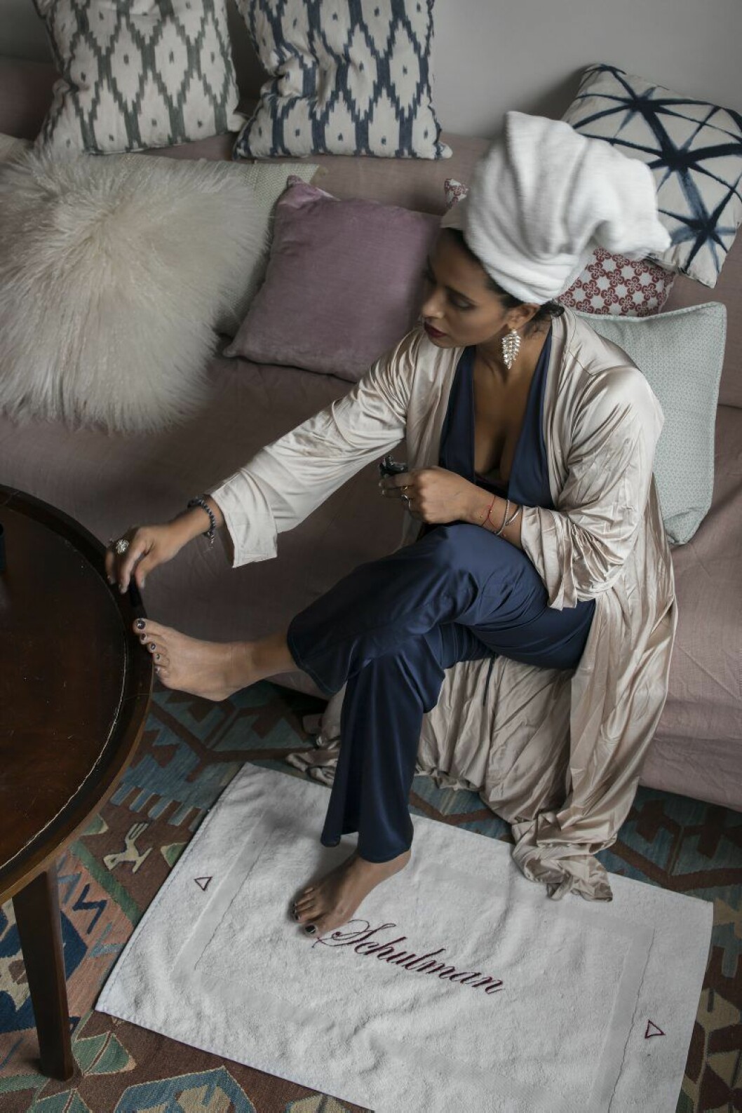 Anitha i sin morgonrock och pyjamas från Chambres. Kudde bakom huvudet från Lagerhaus. Örhängen Caroline Svedbom, ring Swarovski. Badrumsmattan har hon designat själv. Den är gjord i frotté för att enkelt kunna tvättas. Anitha Clemence