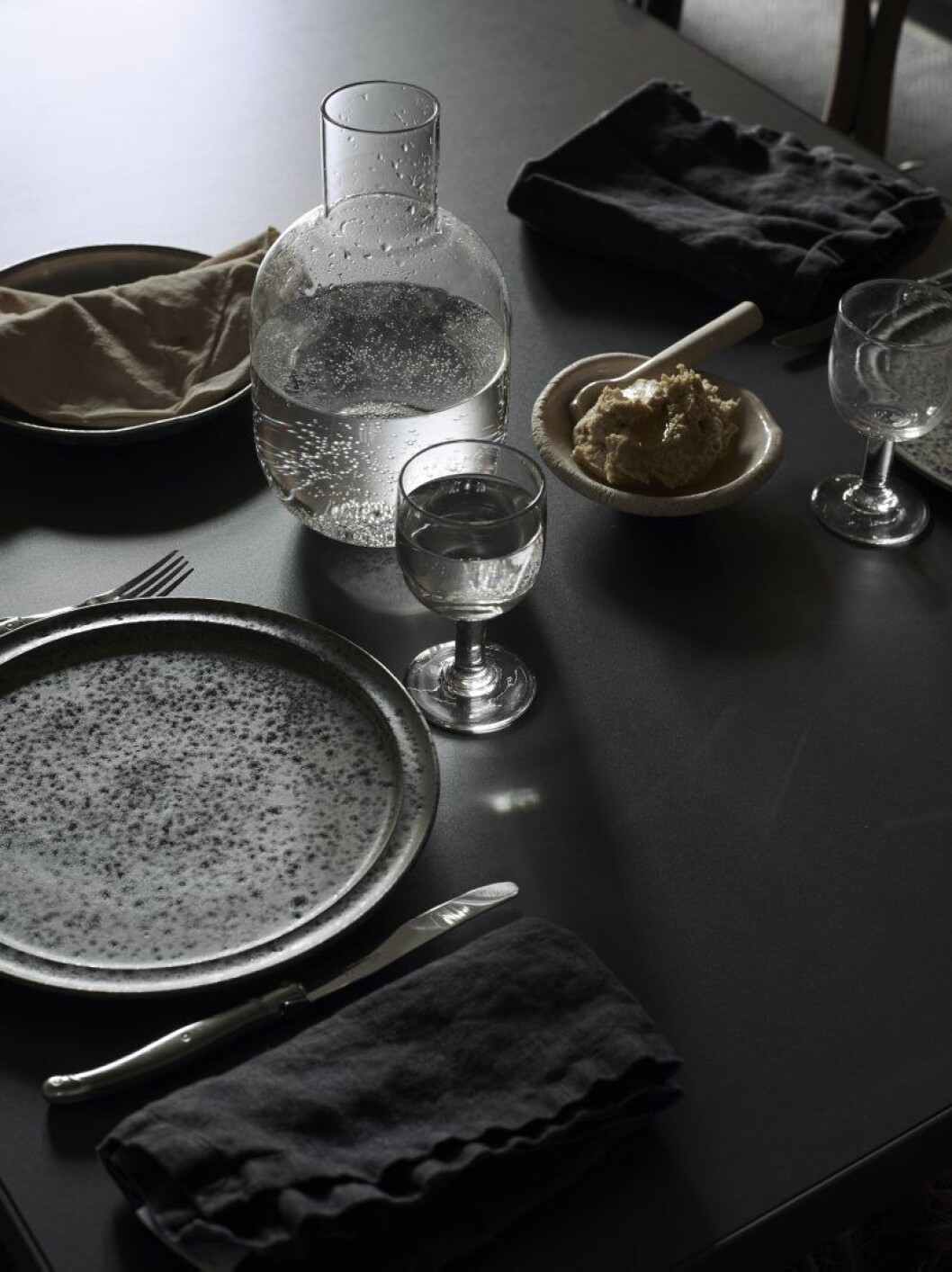 På bordet karaff av Carina Seth Andersson för Hope, Tallrikar från KH Würtz och besticken från Laguiole. Smörskål och sked av Gustaf Nordenskiöld. Glasen är gamla franska bistroglas som Lotta samlat på sig från loppisar i Frankrike.