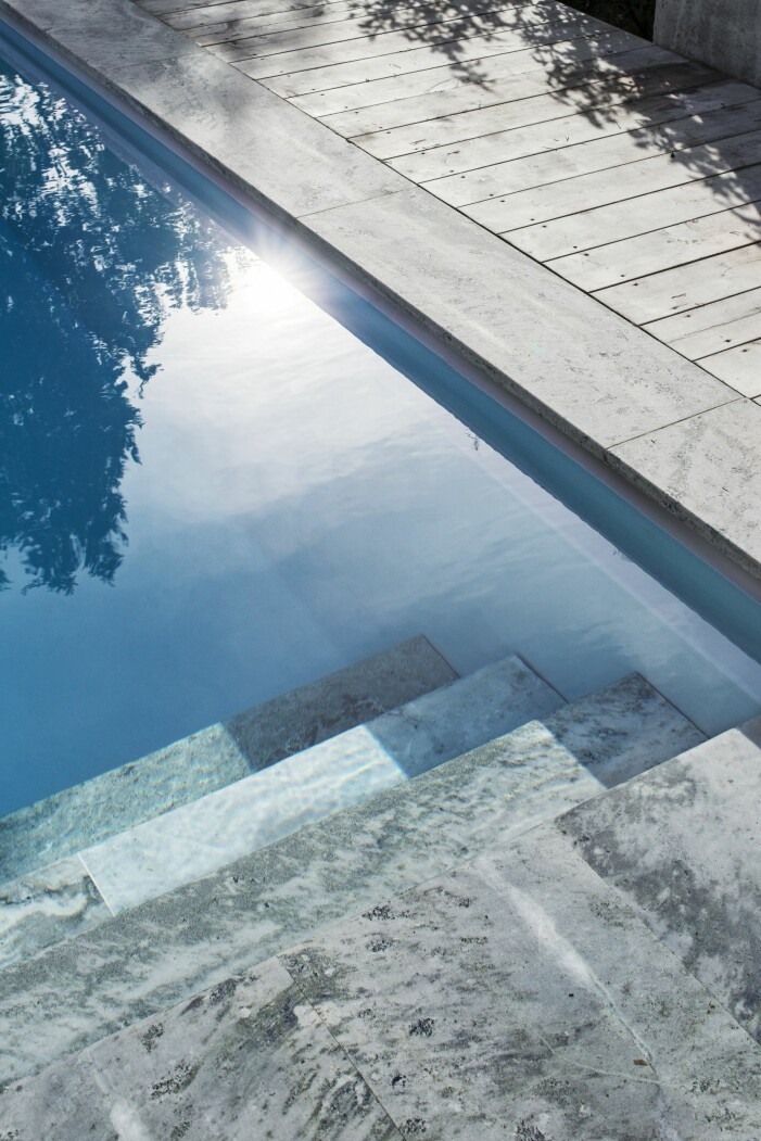Poolen är invändigt klädd med ljusgrå liner, men ramas in av sandsågad kolmårdsmarmor och organowood. I stället för stege finns en stenlagd trappa som leder ner i det blå. Pool