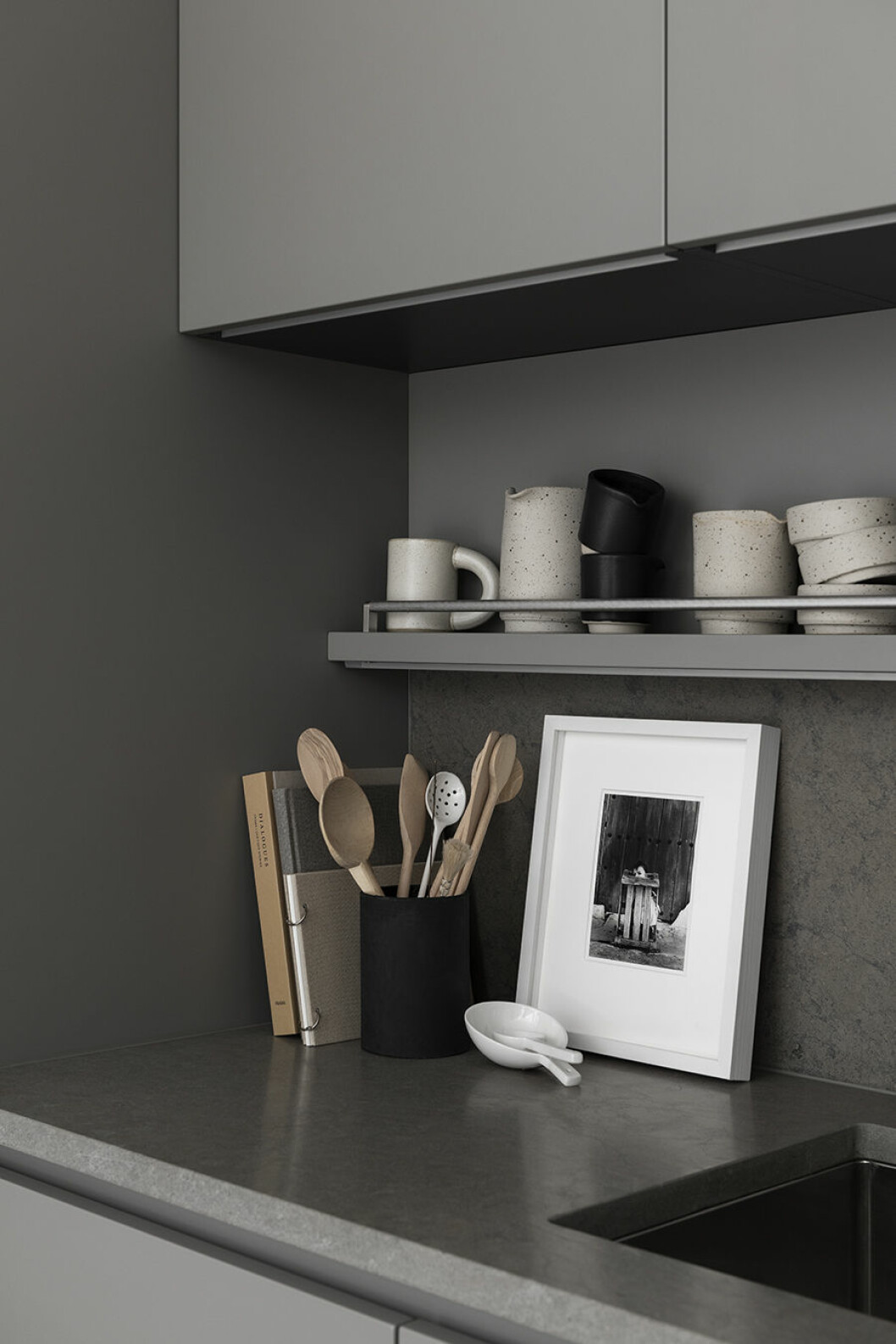 Vit och svart keramik <em>Aj Otto</em> från Frama och mugg med handtag av Olivia Fiddes och Faye Toogood. Träslevar från Riktig, Stelton, vit porslinssked från Strax, konst via Moderna samlare. 79 PARK köksbänk