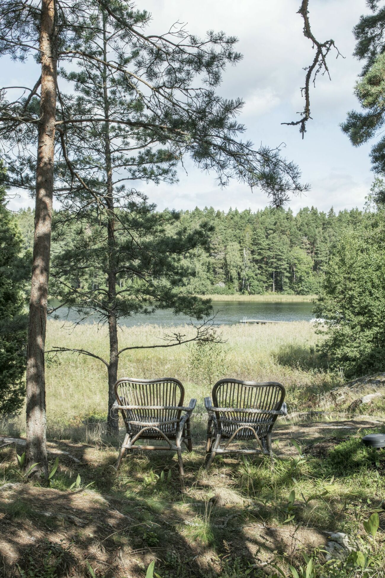 Två stolar med utsikt över skog och vatten.