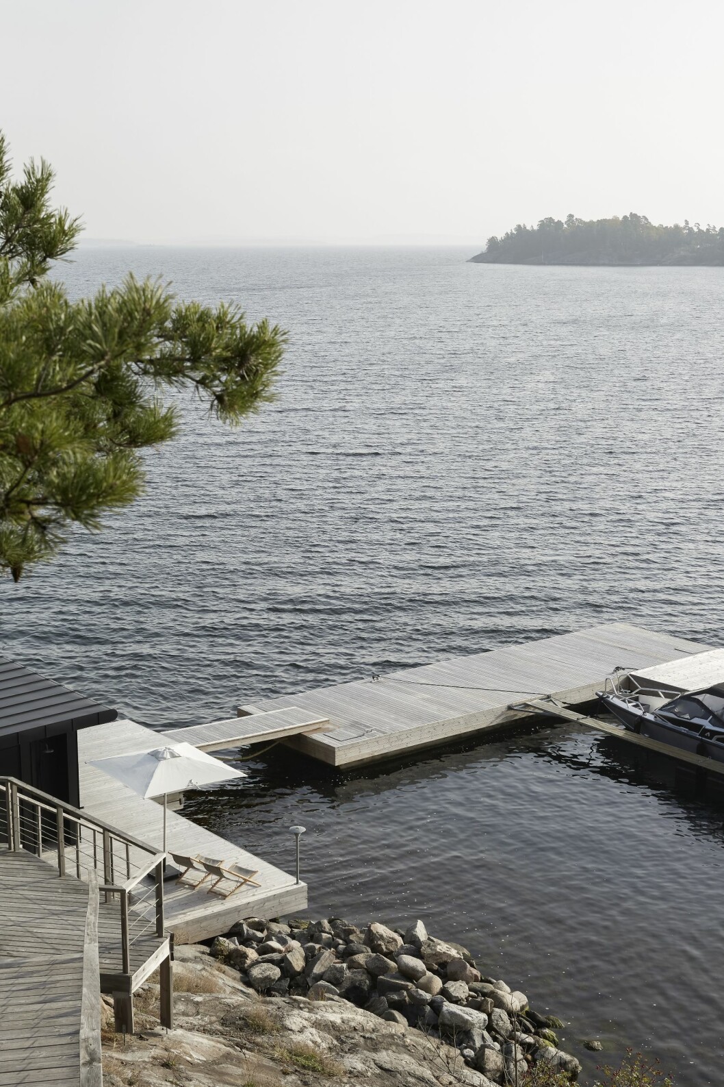 En lång trappa leder ner till båtbryggan och bastun vid klipporna, ritad av Jordens arkitekter. Solstolar H55 från Skaargarden och parasoll från Cane-line/Länna möbler. Hus på Dalarö stylat av Pella Hedeby.