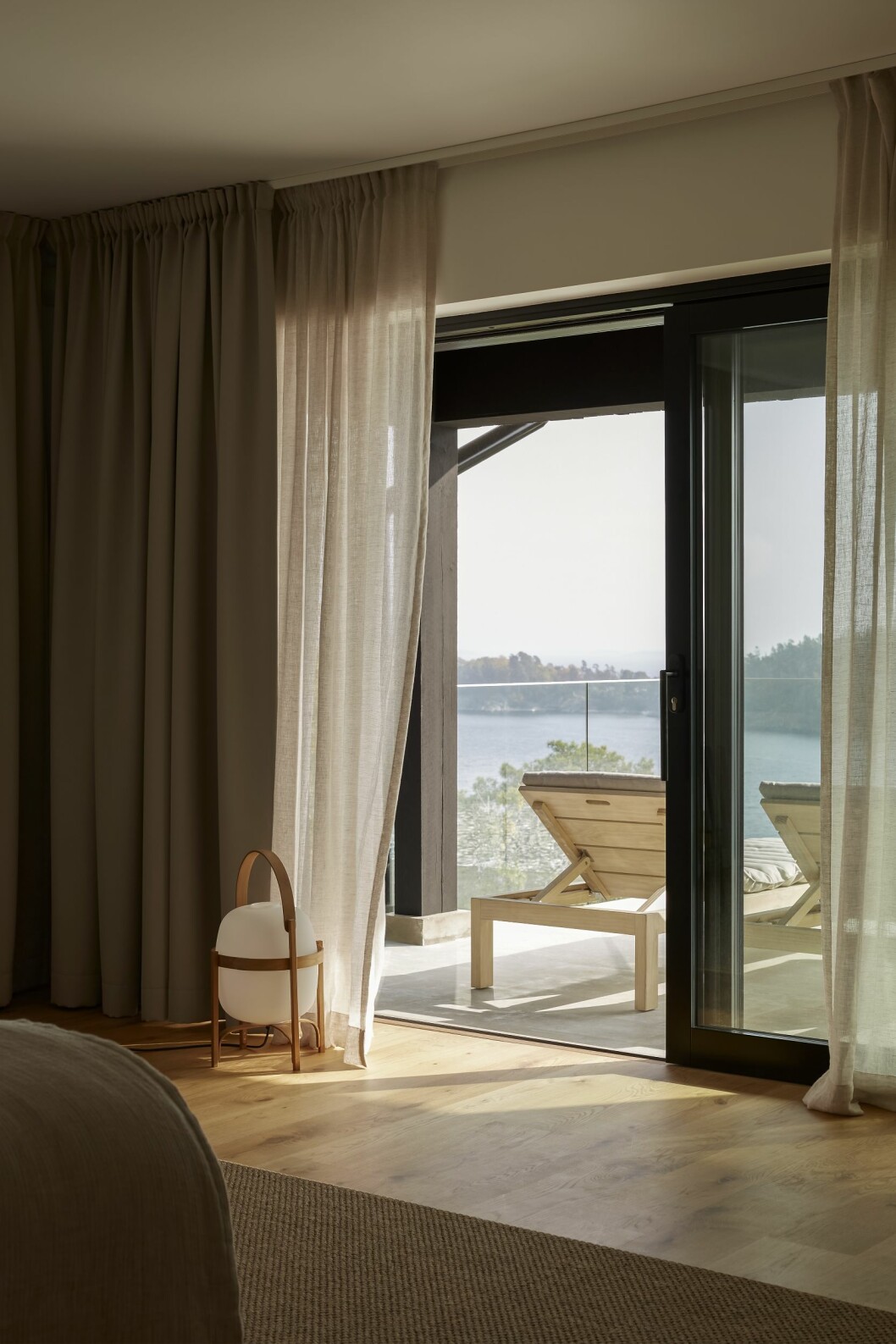 Från sovrummet på övre plan kan man öppna upp ut mot terrassen. Linnegardiner, Gotain. Golvlampa Cesta, Santa & Cole. Sisalmatta, Kjellbergs. Solsängar, Tine K home. All inredning beställd på Målarboden. Hus på Dalarö stylat av Pella Hedeby.