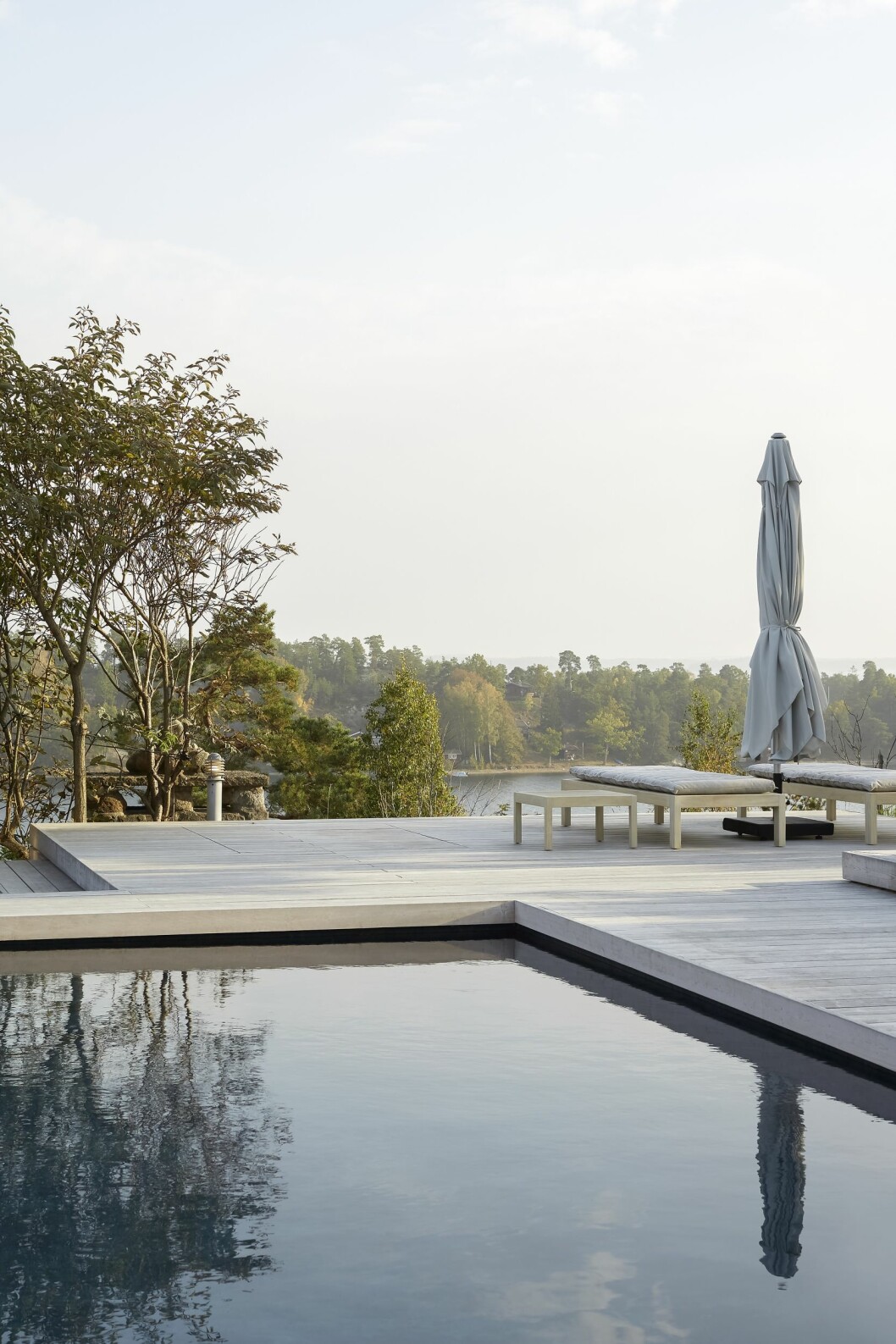 Havsbad eller poolbad, varför tvingas välja? Tralldäcket är byggt av kiselbehandlad Organowood. Solsängar, Tine K home. Parasoll, Cane-line. Hus på Dalarö stylat av Pella Hedeby.
