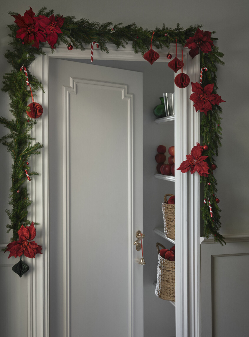 Polkagrisar, röda julstjärnor och klassiskt rött hör den traditionella julstilen till. Girlang runt dörr med julstjärnor i rött och polkagrisar