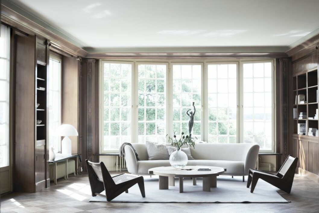 Soffa Dandy från Massproductions, Annaleena studio, soffkuddar Astrid, <p></p><p>soffbord Rio table av Charlotte Perriand, Nordiska galleriet. På soffbordet </p><p>vasen Pallo av Carina Seth Andersson, Svenskt tenn. Rottingfåtöljer av Pierre Jeanneret, Galerie Maison Première, mattan är från Kasthall. Vaser i hyllan </p><p>Kåge-keramik, Jacksons. Skulpturen i fönstret är original från Åkerlundska villan.</p>