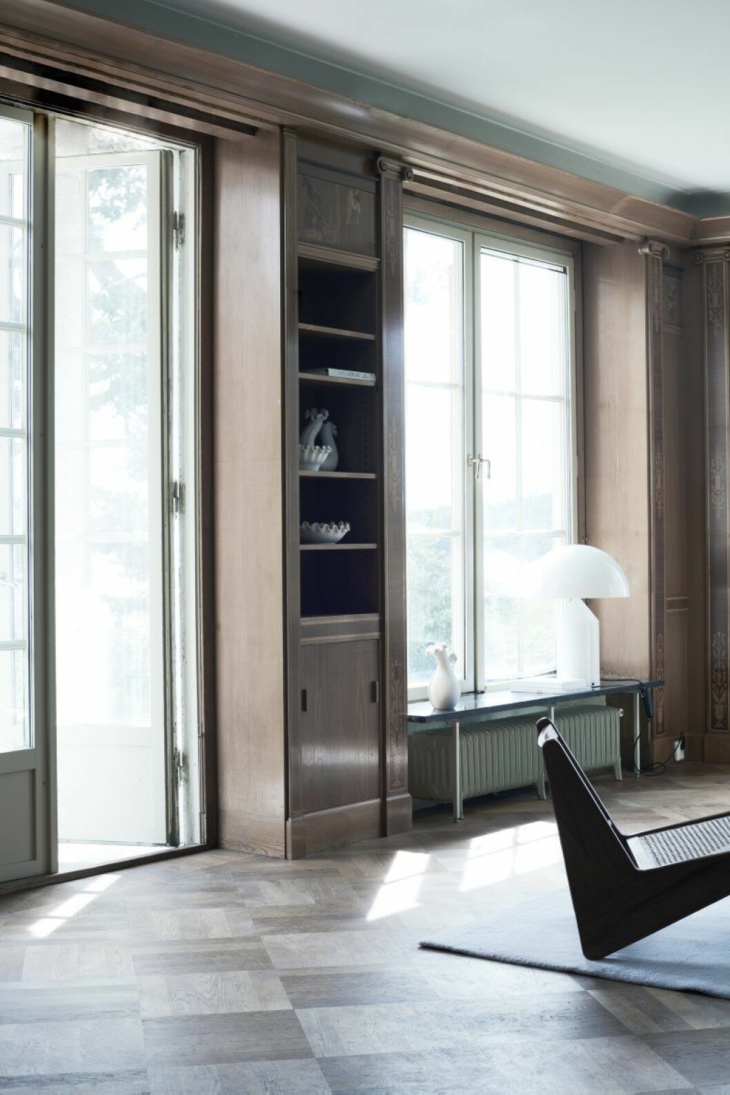 Rottingfåtöljer av Pierre Jeanneret, Galerie Maison Premiere, mattan är från Kasthall. I fönstret lampan Atollo från Oluce. Vaser i hyllan Kåge-keramik, Jacksons. Skulpturen i fönstret är original från Åkerlundska villan.