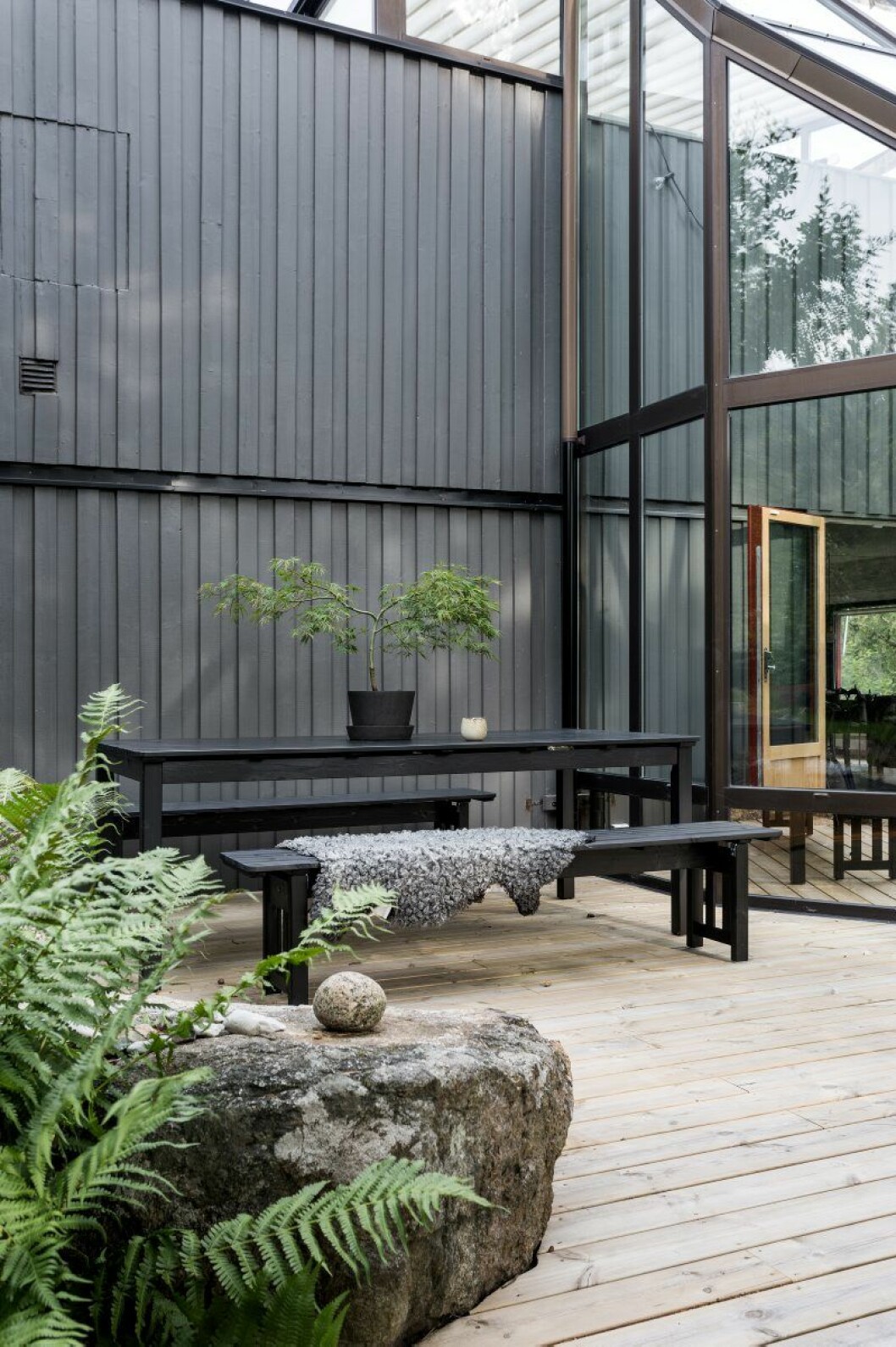 Terrassen är ritad av inredningsarkitekten Anya Sebton och binder samman huset med trädgården. Här finns grill och matplats, några bänkar och solsängar. Bord och bänkar från Ikea, mugg på bord från KH Würtz och en kruka från Carina Seth Andersson. Alla växter kommer från Zetas trädgård, som ligger i närheten. altan och orangeri