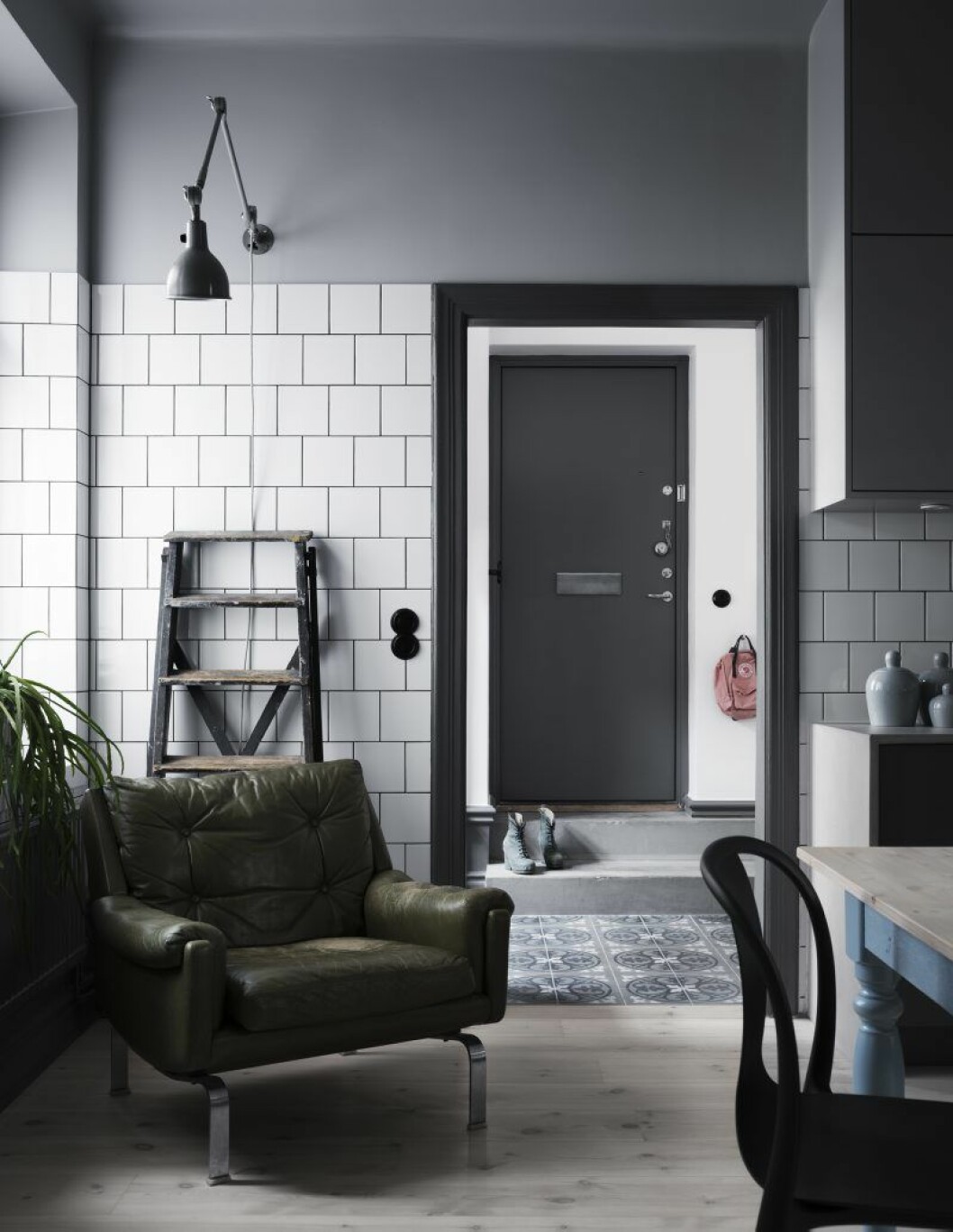 Trappan ner från ytterdörren vittnar om lägenhetens fabriksförflutna. Hallens mönstrade betongplattor fortsätter in i det intilliggande badrummet och knyter an till lägenhetens sekelskiftesarv. Den olivgröna 60-talsfåtöljen är ritad av Karl Erik Ekselius för JOC möbel AB. arkitektparets lagenhet foto kristofer johnsson1