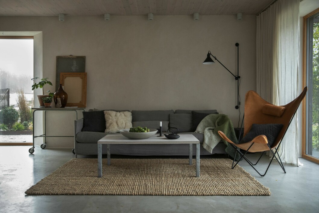 Naturens färgskalor och material går igen inne. Läder, ull, sisal och lin står för de mjuka inslagen. Grönmelerad yllefilt, Design Lina Johansson. Vit ullkudde, Classic collection. Fåtölj, Ox Denmarq. Vägglampa modell 214, Lampe Gras. Bord med skiva i betong, Grafitgrå. Brysselkål direkt från trädgården. Betongfat, Ta form konstgjuteri. Arkitektritade trähuset – med magiskt orangeri