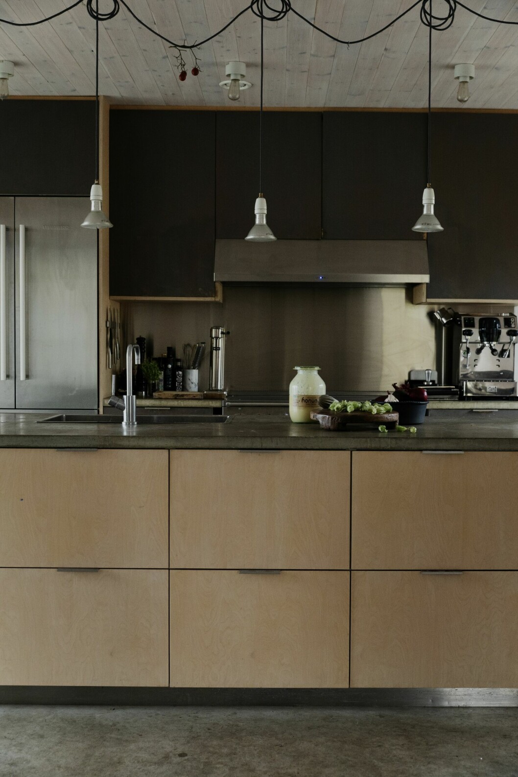 Köket står inför en förändring och kommer att få nya skåpluckor, troligen i vaxad valchromat. Lampor, Ifö. Stänkskydd och golvlist i rostfritt stål. Arkitektritade trähuset – med magiskt orangeri