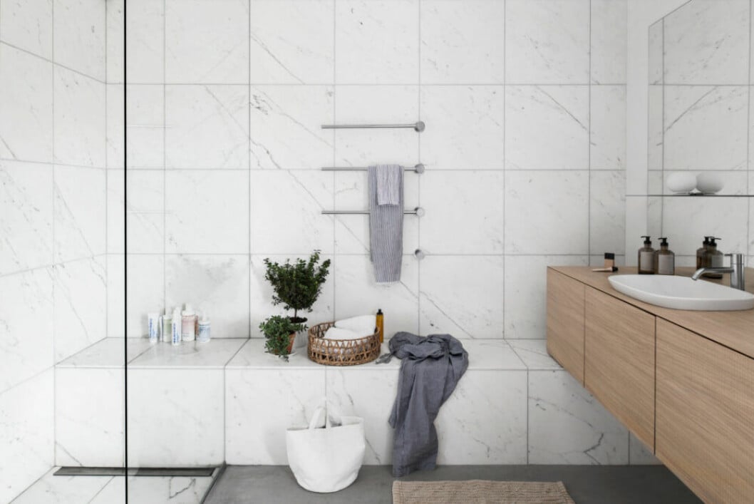 Bänken i badrummet var från början ett sätt att dölja rören, men blev en funktionell detalj. Bänken är platsbyggd av Asplund studio. Handduks tork från Vola.Lampa Mini globall, design Jasper Morrison för Flos. Badrummet i marmor hos Asplund.