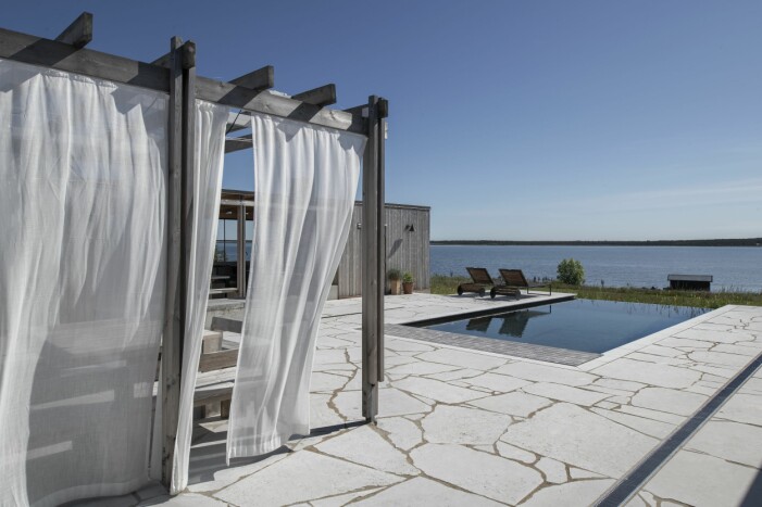 The Great Gatsby på Gotland. Infinity-pool i svartpigmenterad platsgjuten betong.Gotländsk kalksten runt om. Mats W Walter jobbade i blåställ med hammare och vinkelslip för att visa hur stenen skulle läggas. pool och uteplats