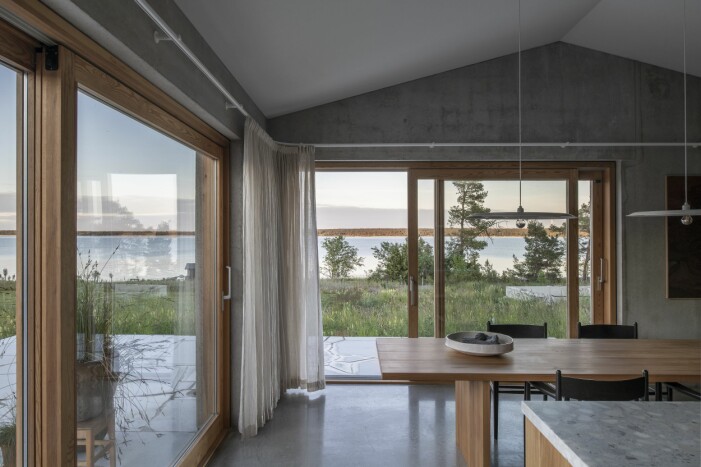 Utsikt från middagsbordet, ritat av arkitekterna, tillverkat i massiv alm. Trä och textil ger rummen en hemtrevlig atmosfär. Fönsterkarmar i massivt trä. Middagsbord med fönster runt om.