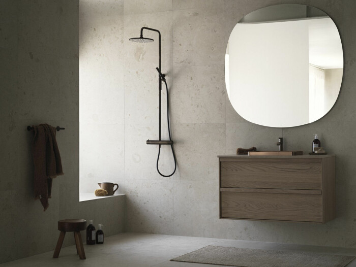 Mjukt och harmoniskt med kommod i ek från svenska Haven och väggar i <em>Norrvange Ivory</em> från Bricmate. Spegeln kommer precis som kommoden också från Haven. Foto: Ragnar Ómarsson Styling: Pella Hedeby för Bricmate badrum i kalksten och trä med stor rund spegel