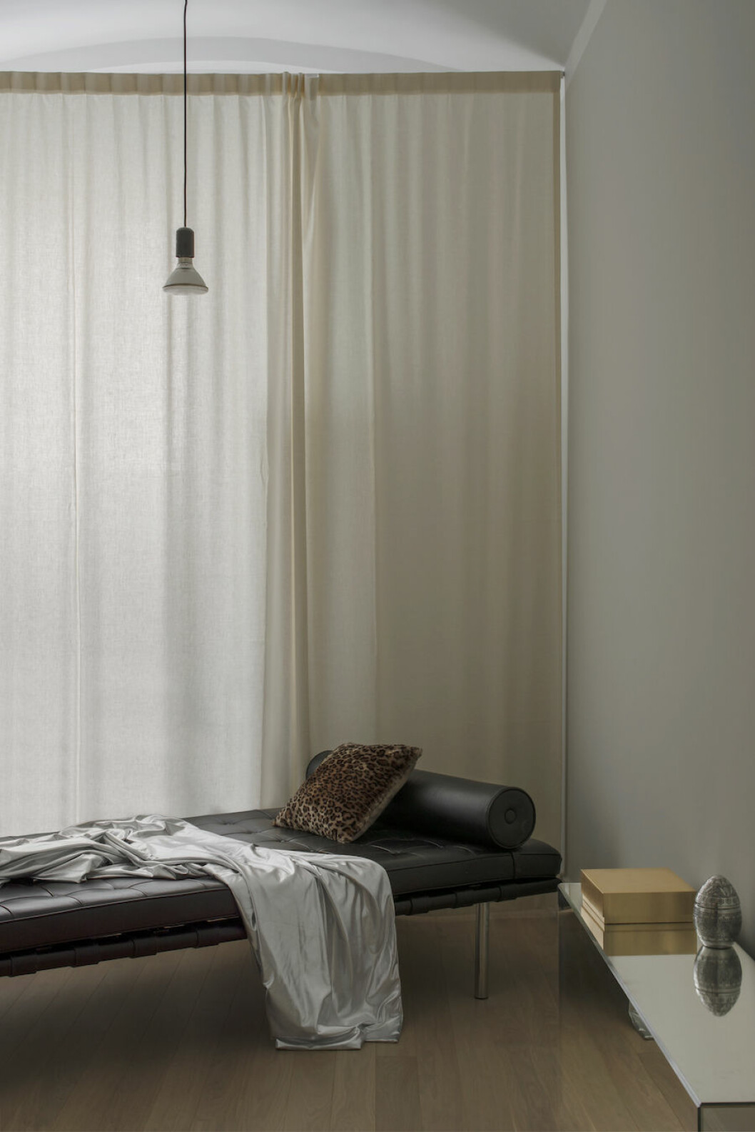 <em>Överkast från Magniberg, dagbädd Barcelona av Mies van der Rohe för Knoll. Taklampa från Andreas Martin-Löf arkitekter och egendesignat spegelbord.</em> Bild på dagbädd av Mies van der Rohe, silvrigt överkast från Magniberg och egendesignat spegelbord.