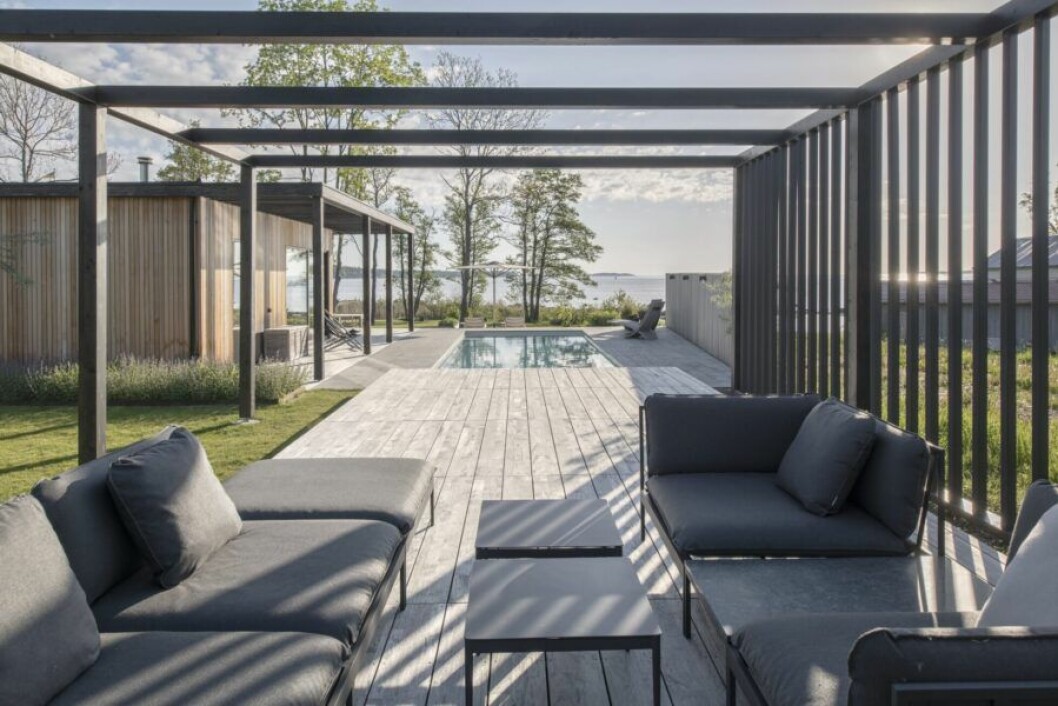 Bönan, loungefåtöljer med granitbord, design Studio norrlandet, Anholt, bord, design Susanne Grønlund. H55-stolar från 1955, design Björn Hultén, uppe i vänster hörn. Nozib, solstol, design Nils-Ole Zib uppe i högra hörnet. Hela denna uteplats är på hjul och kan skjutas som ett lock över poolen.