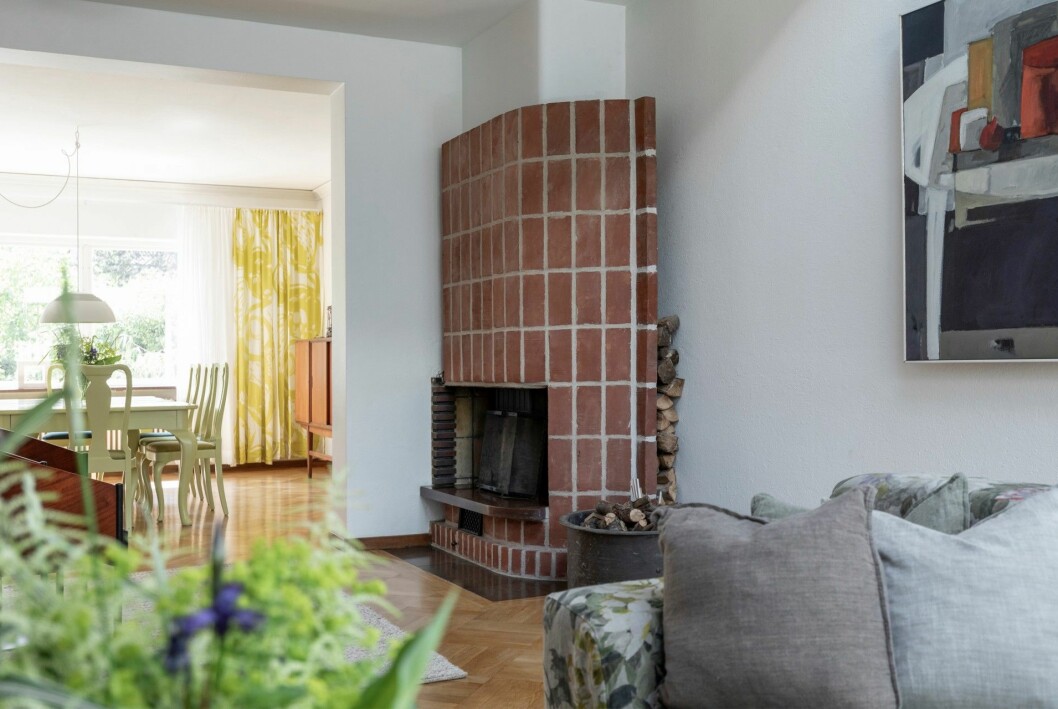 En öppen spis i rött tegel och med inbyggd vedförvaring. Kika in i arkitektritade 40-talsvillan.