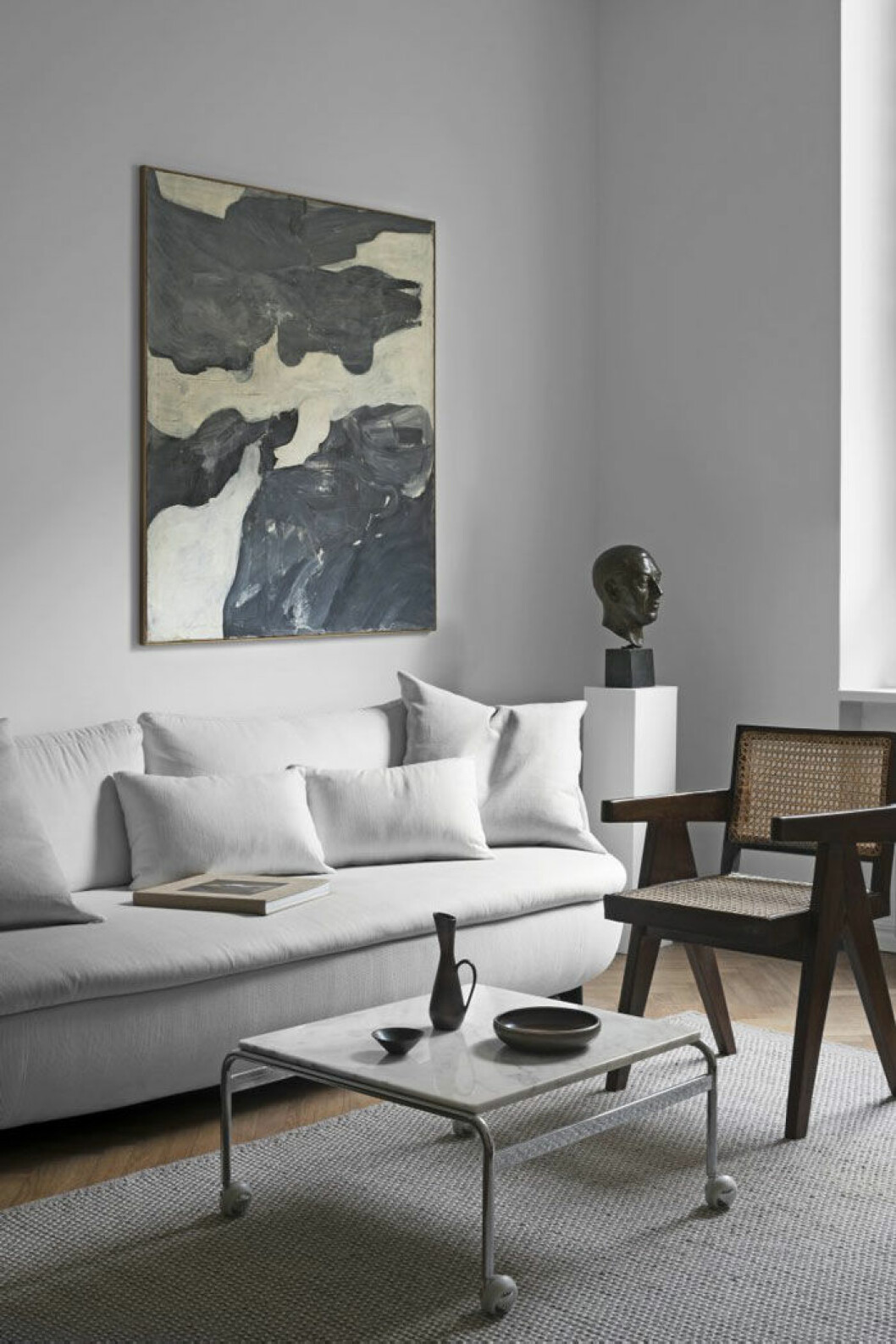 Oljemålning, Bertil Berntsson, 1963. Skulptur i brons, Tore Strindberg, 1934. Soffa Bart canapé, design Moooi works/Bart Schilder för Moooi. Soffbord Karin, design Bruno Mathsson för Dux. Ovanpå står lergods av Carl Harry Stålhane för Rörstrand. Trästol Office chair, design Pierre Jeanneret omkring 1953. Ullmatta vintage.