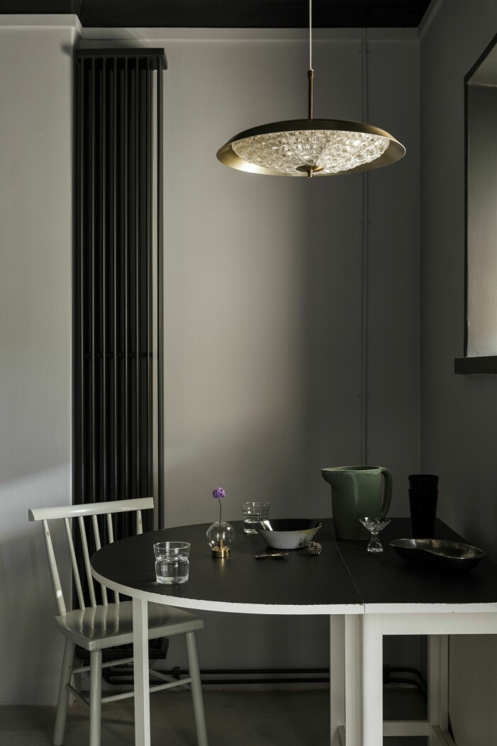 Ovanför matplatsen hänger en lampa av Carl Fagerlund för Orrefors. Stol och bord, vintage. Vattenglas Krås, Straight design studio för Designtorget. Vas Orbis, Straight design studio för Klong. Skål An ode to enamel, Sepp Müller för Crooked concept. Karaff Sinnerlig, Ilse Crawford för Ikea. Martiniglas, vintage. Njurskål, vintage. Glas Viktigt, Ingegerd Råman för Ikea. Designerns minietta i Stockholm – funktion och dynamik