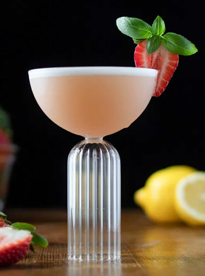 skummig drink i högt glas med jordgubb och basilika