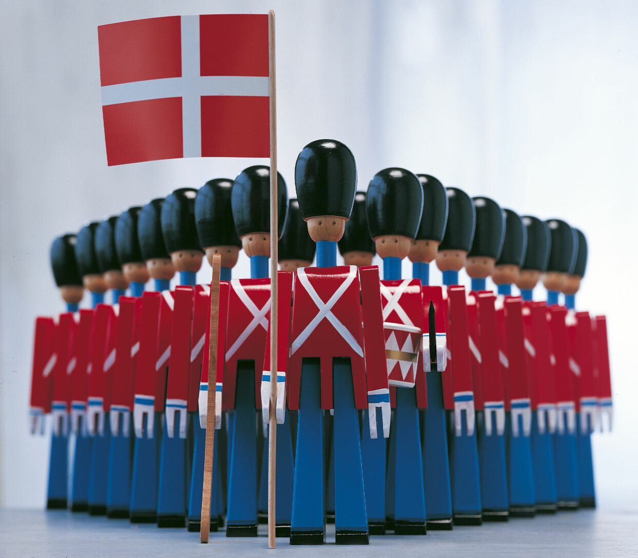 Dronningens soldater på marsch. För den klassiska fanbäraren har utvecklingen gått framåt. Numera är flaggan gjord av tyg, och inte i papper som på bilden. Cirkapris i butik för soldat, ca 22 cm, med flagga är cirka 750 kr. Dronningens soldater med dansk flagga i handen – design av Kay Bojesen.