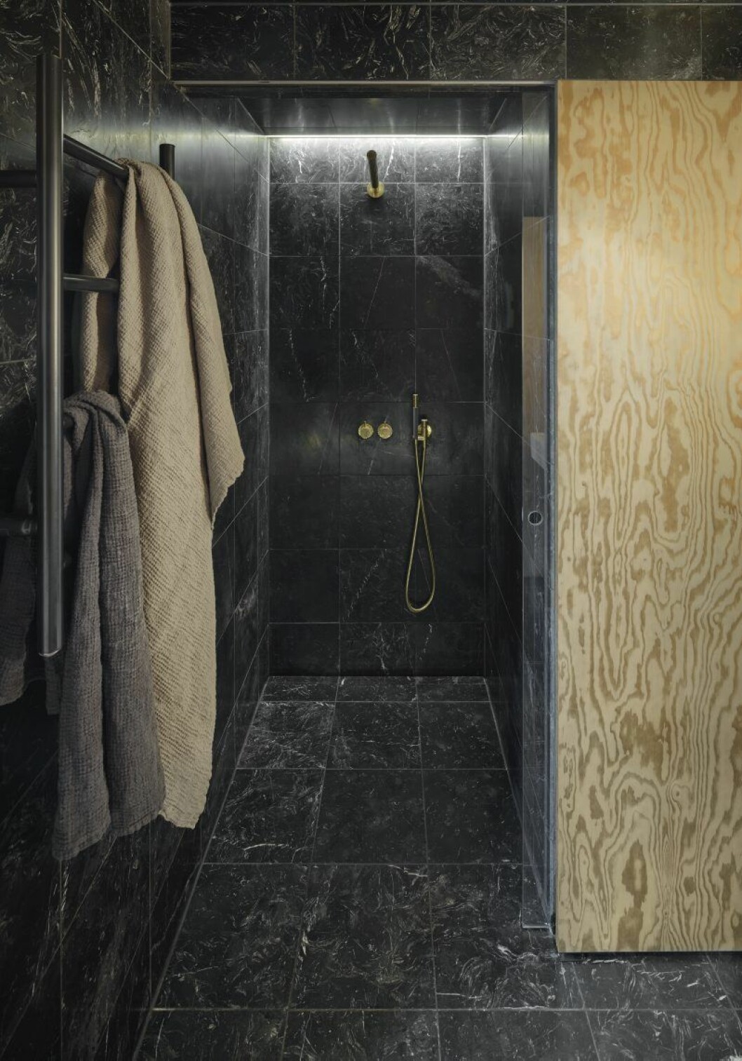 Badrummet är inrymt på en yta in mot berget bakom sovrummet och är därför utformat som en förfinad grotta i Nero Marquina-marmor. Den skjutbara plywoodskivan döljer tvättmaskinen. Duschblandare, Vola. Sommarhus Andreas Martin-Löf