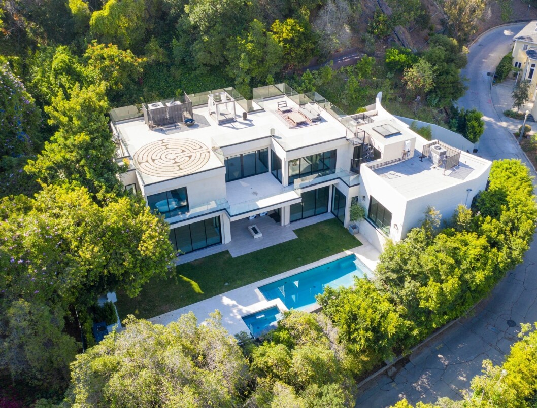 Flygfotot visar en villa i flera plan omringad av grönska, med pool och sociala ytor utomhus. Flygfotot visar en villa i flera plan omringad av grönska, med pool och sociala ytor utomhus.