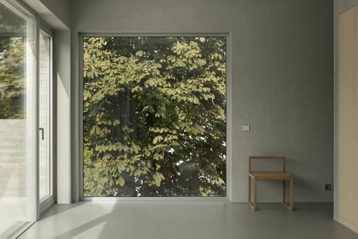 Stora glaspartier släpper in de skiftande årstiderna i huset. Stol The Outline 02, design Fumihito Ohashi för Bonnibonne. Stort glasparti med en stol.
