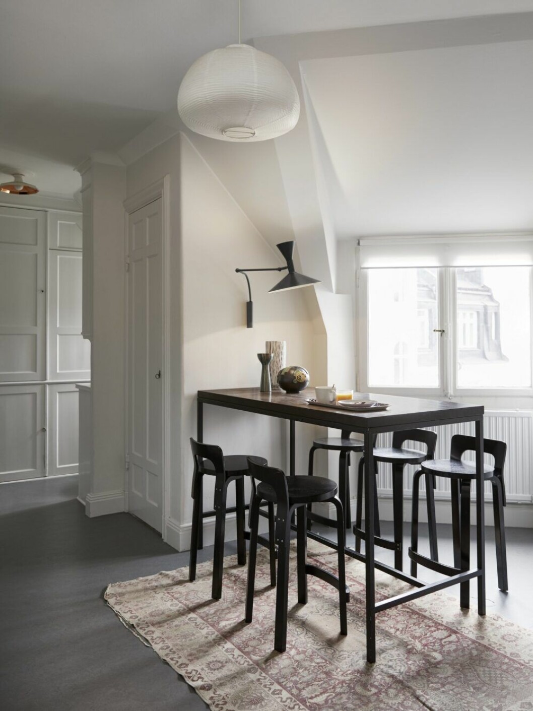 Smart matplats i hörnet. Vägglampa Lampe de Marseille, Le Corbusier/Nemo, barstol K65, Alvar Aalto för Artek, barbord, specialsnickeri.