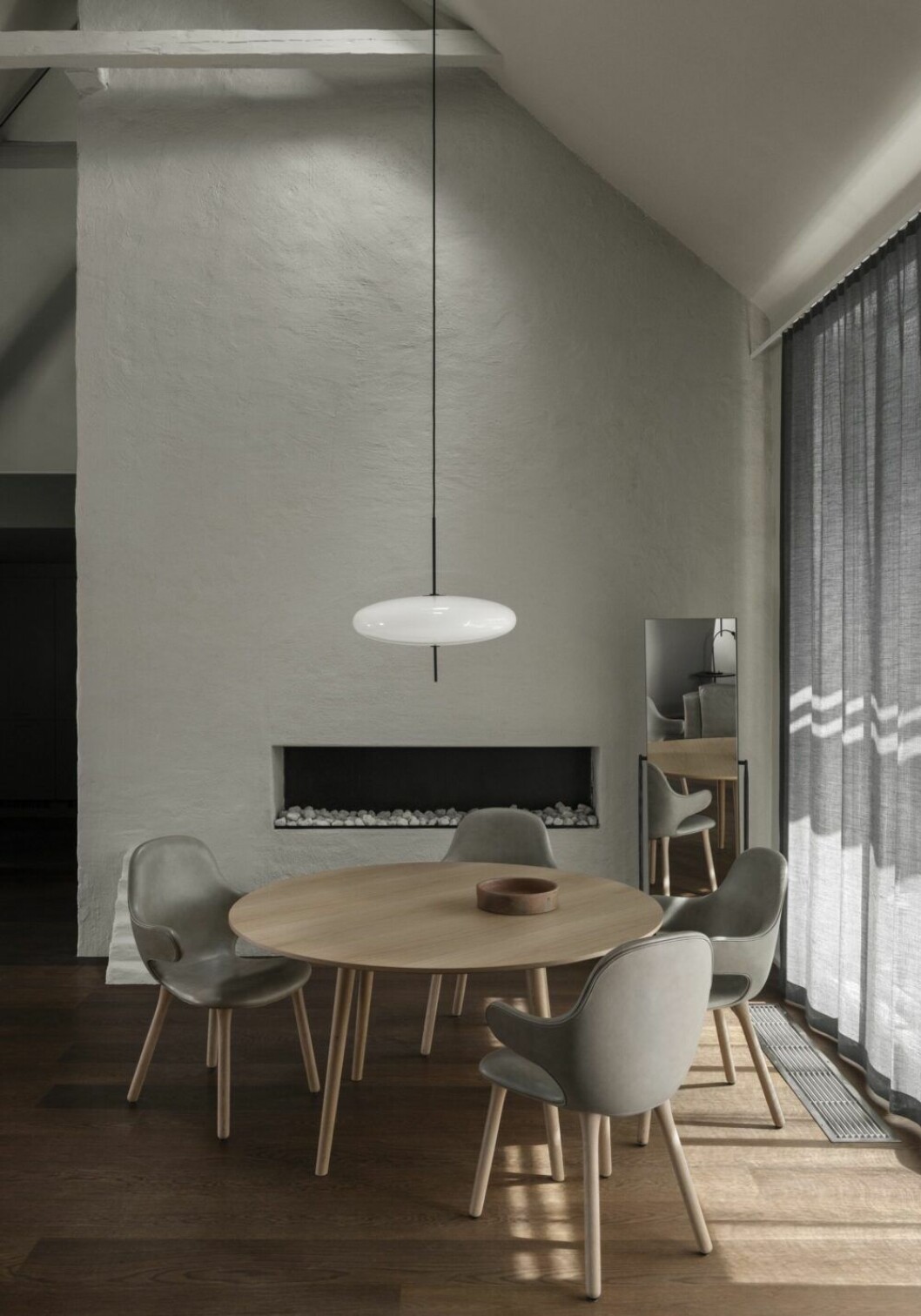 Samlingsplats vid utsikt och öppen spis. Bord In between table, ritat av Sami Kallio för &Tradition. Stolar Catch chair, design av Jamie Hayon för &Tradition. Lampan är designikonen Model 2065, ritad av Gino Sarfatti 1950 (Astep). Spegel Officina mirror, ritad av R&E Bouroullec för Magis.