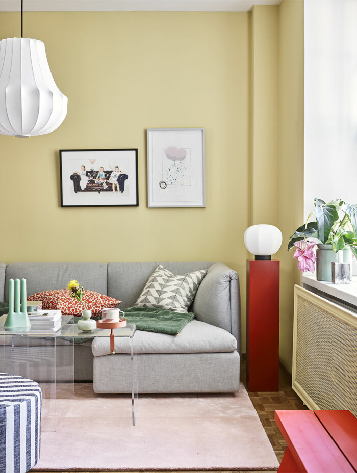Hos Beckers är ett av 2021 års färgteman just <em>Joyful yellow,</em> här med kulören <em>Stäpp 612</em> målad på väggen intill den grå soffan. Foto: Beckers gult hos Beckers i kulören Stäpp 612