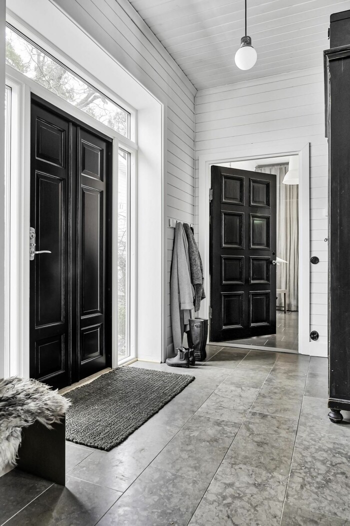Hallen med tre meters takhöjd och kontrasterande svarta dörrar. hall med svarta dörrar och vita väggar