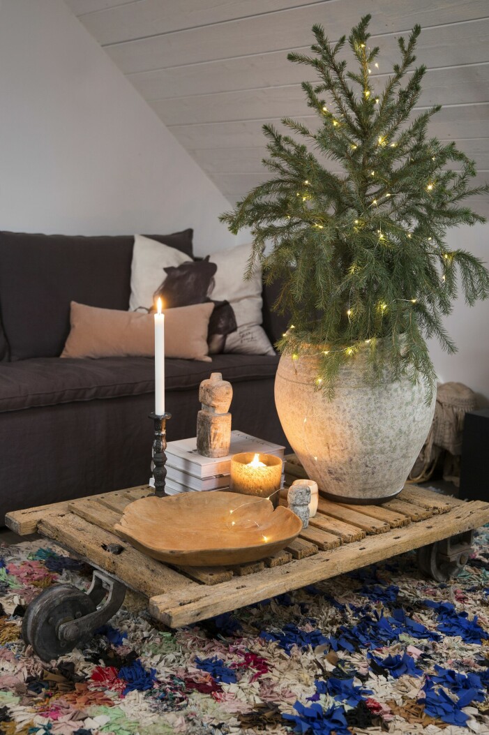 I sovrummet finns plats för en mysig soffa piffad med kuddar. Det låga bordet på hjul framför är ett fynd från Instagram. Träfat från Fira Habitat, gran i urna från Madame Plantier. Julhem floristens gröna jul vardagsrum