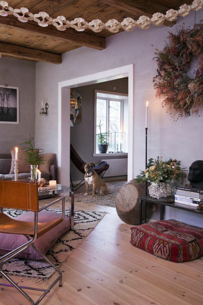 Hunden Bob håller koll. Kransen som Anna har gjort innehåller bland annat pampasgräs, färgad asparagus, torkat lin, lavagrenar, rosépeppar, brudslöja och eukalyptus. Golvpuffar, vintage från Reunion Home, träfat, vintage, samt ljusstake från Madame Plantier. Julhem floristens gröna jul vardagsrum hund
