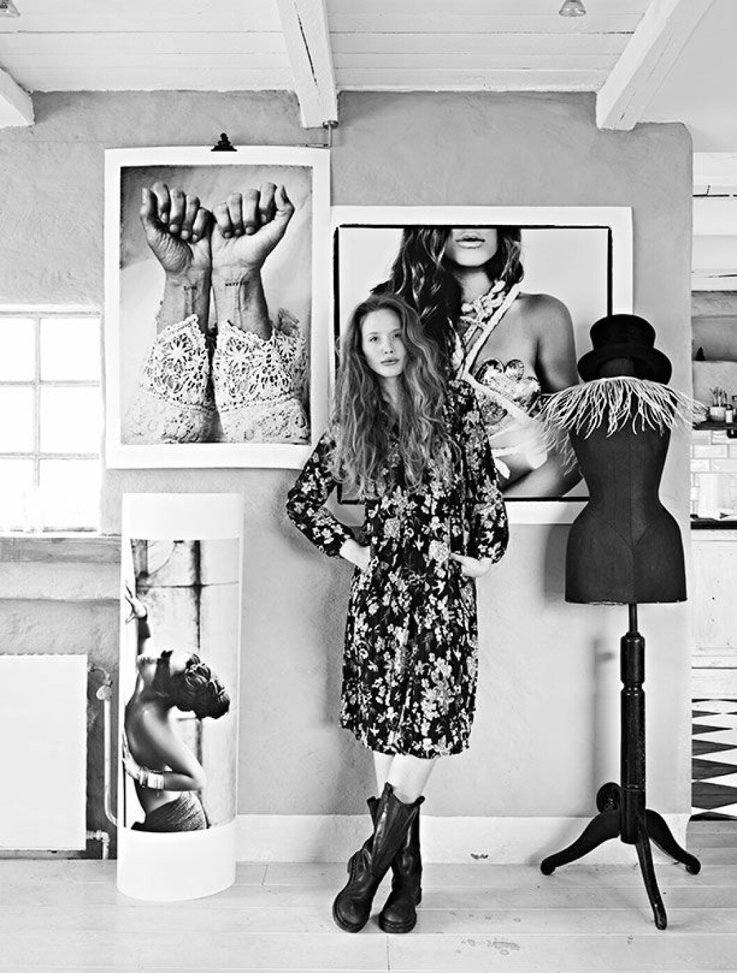 <em>Hannah bor och arbetar i den lilla stugan. Här står hon framför två av sina egna fotografier som säljs via lovewarriors.se. Hannah plåtar alla deras produkter samt följer med på deras resor och väljer ut föremål som säljs via deras hemsida.</em> hemma hos hannah lemholt 4