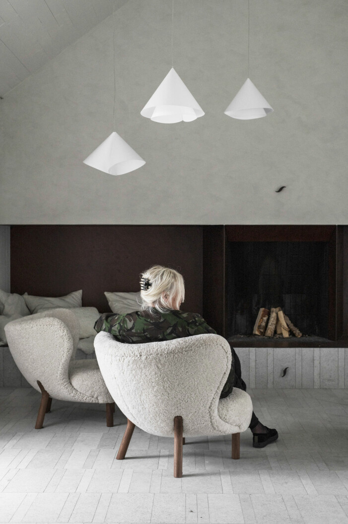 Karin framför den öppna spisen i ladan. Fåtölj Little Petra av &tradition, lampa Virvel av Ingegerd Råman för Örsjö belysning. Hemma hos Karin och Gert Wingårdh på Äggdal