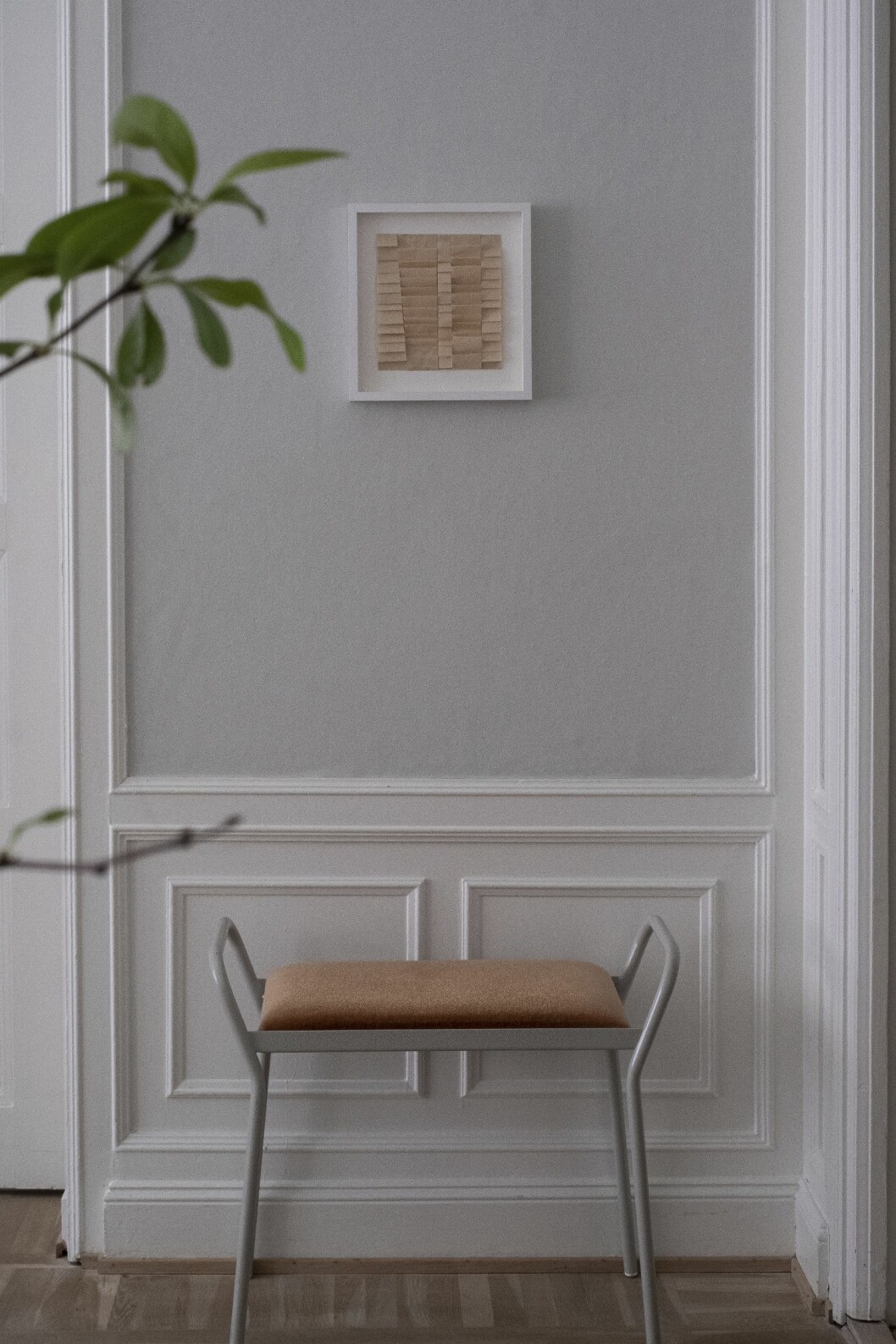 Vardagsrummet har en vacker bröstpanel och ljusgrå väggar. Bänk från Maze interior och konstverk av Åsa Stenerhag.