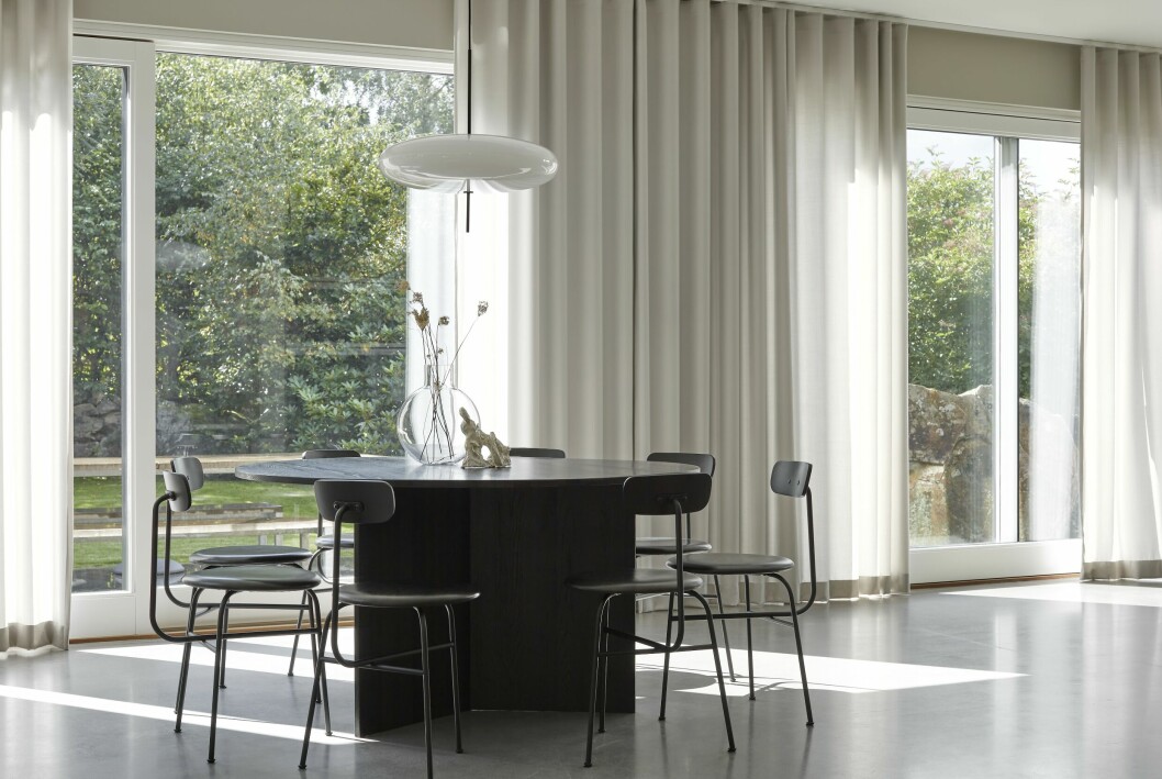 Vid matplatsen vetter skjutdörrar ut mot grönskan på baksidan av huset. Textiler mjukar upp helheten, inte bara vid fönstren utan även längs väggar. Stolar med lädersits, Afteroom dining chair, Menu. Bord, MK design studio. Vas Pallo, Skrufs glasbruk. Lampa modell 2065, design Gino Sarfatti, Astep. Hemma hos MK Design Studios grundare matsal