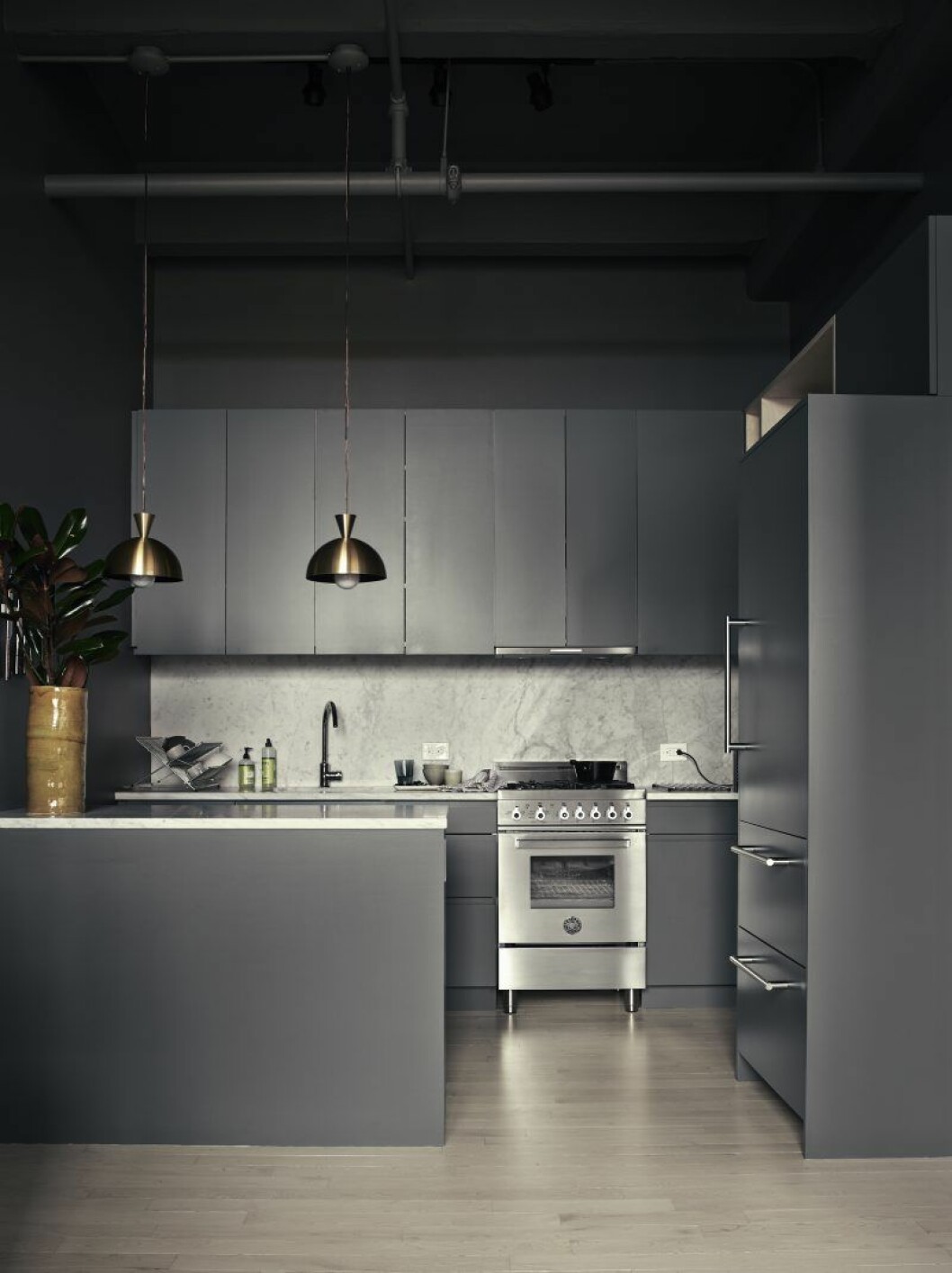 Köket är målat i mörkgrått, plywooden oljade Pia in lite lätt. Skåpstommarna är från Ikea. Luckorna är platsbyggda och har fått samma färg som väggen. Lampor av svensken Alexander Höjer, inköpta i Kapstaden. Hemma hos Pia Ulin Foto Pia Ulin_4