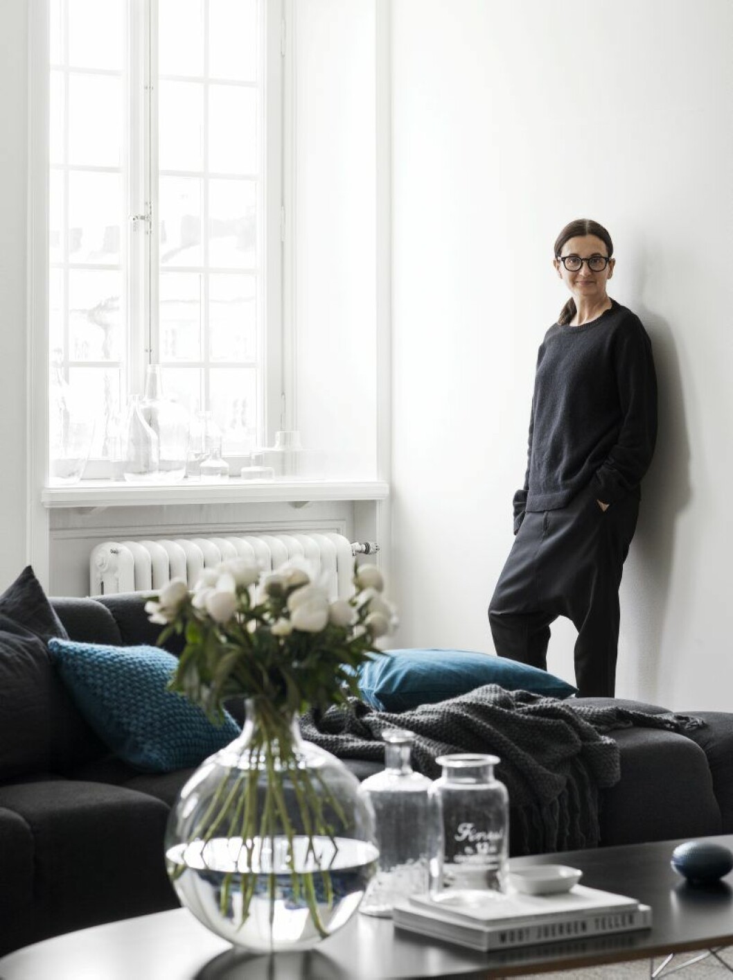 Evelina Kravaev Söderberg i lägenhetens vardagsrum, i förgrunden Carinas Seth Anderssons vas Pallo för Skruf och glas från H&M Home.