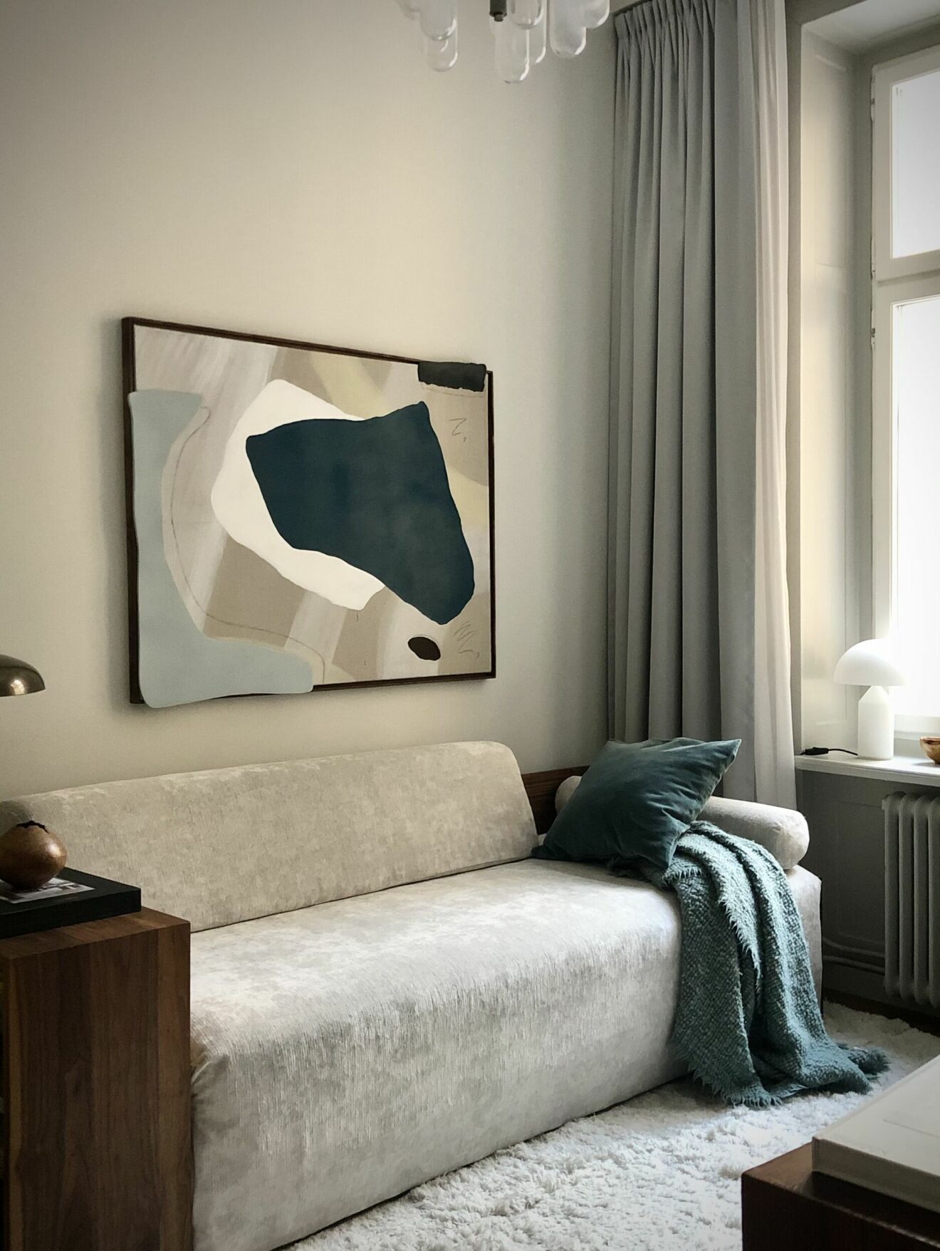 Vardagsrum med beige soffa och abstrakt tavla