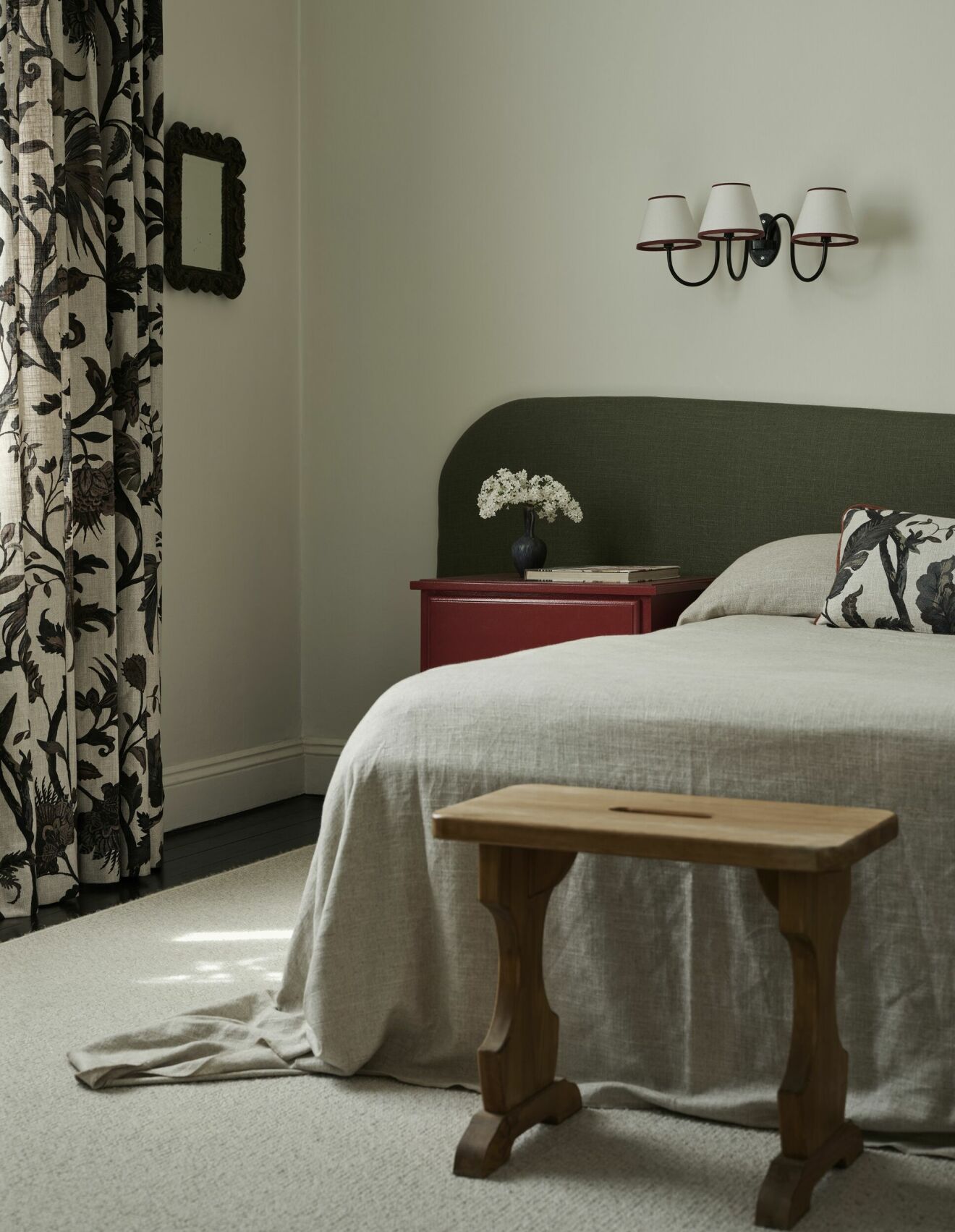 Trearmad ­vägglampa är ­vintage, allmogepallarna som står vid sängens fotända. Gardiner och kudde i Gotain-mönstret Gotnoir.