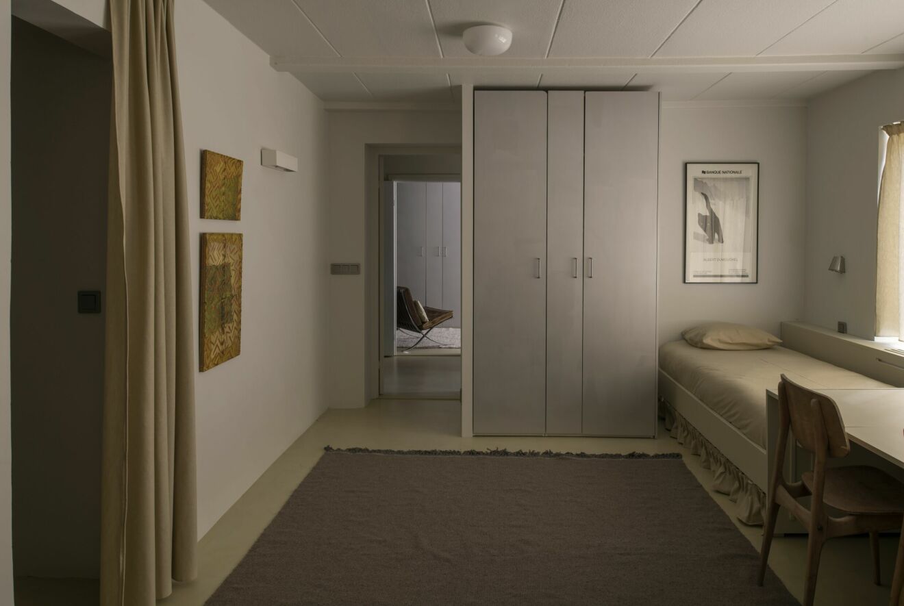 50-talsvilla sovrum garderob i aluminium beige säng gula tavlor handvävd matta